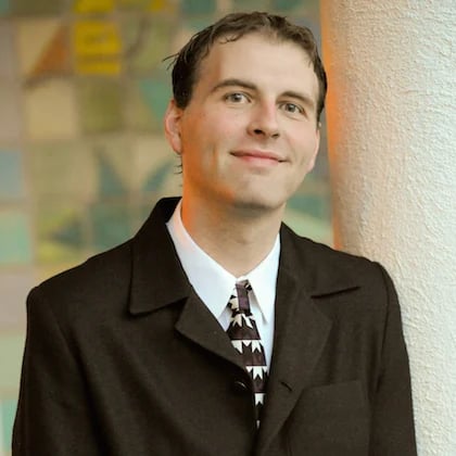 a person in a suit leaning against a pillar