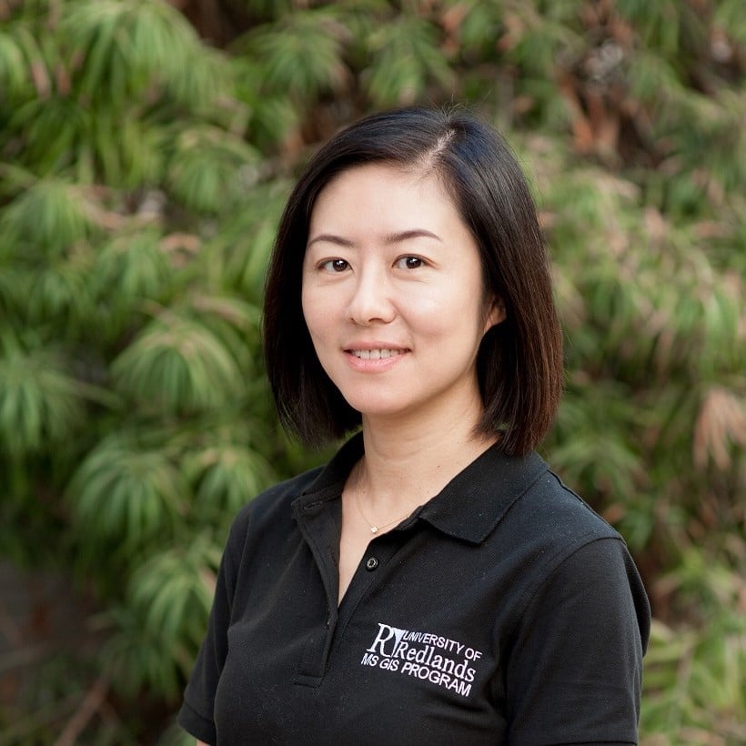 a woman smiling in front of a tree