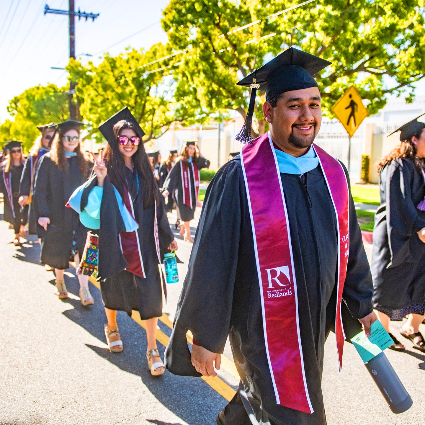 a group of people in graduation gowns and cap and gowns walking down the street