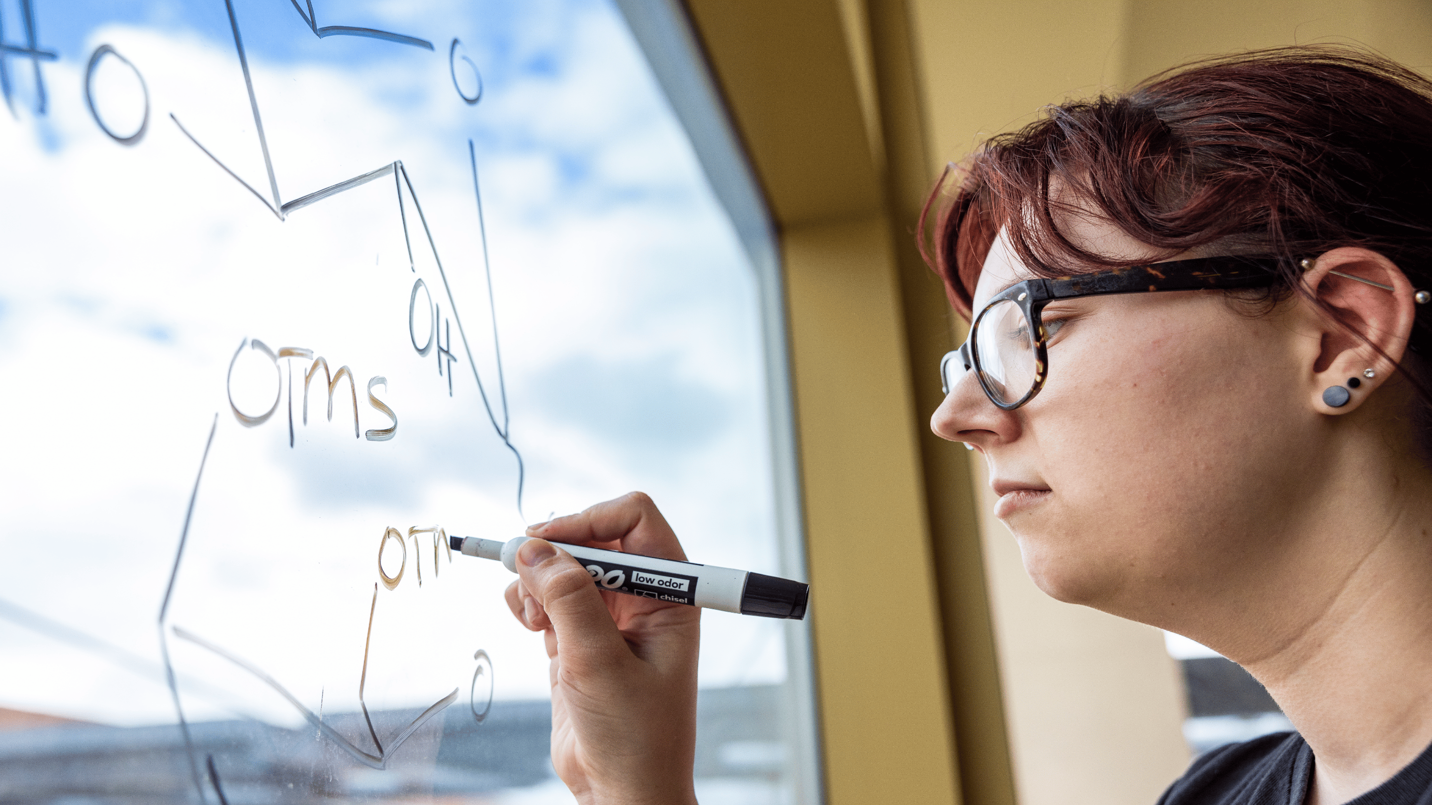 a woman writing on a glass board