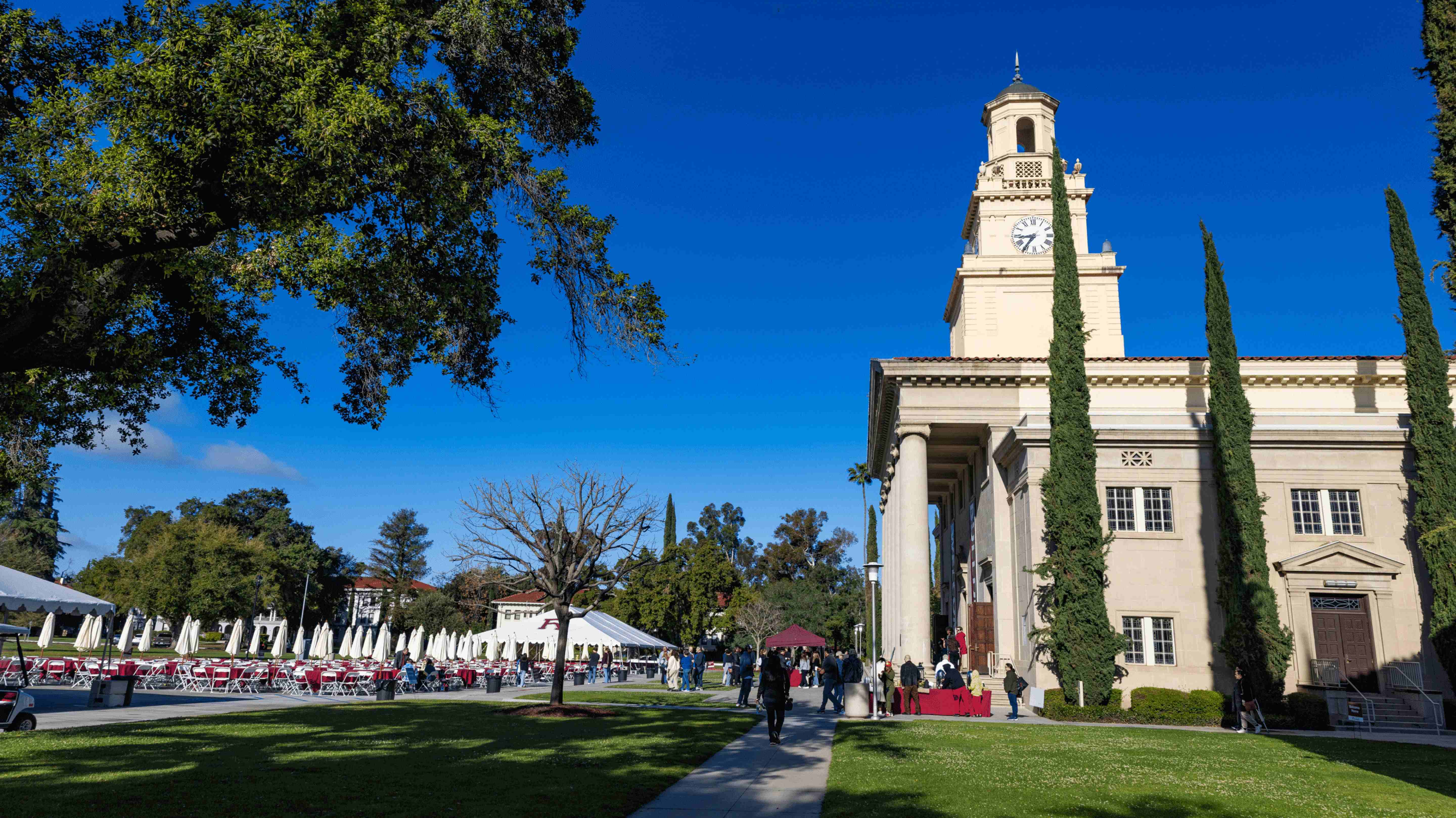 a building with a clock tower and people walking in front of it