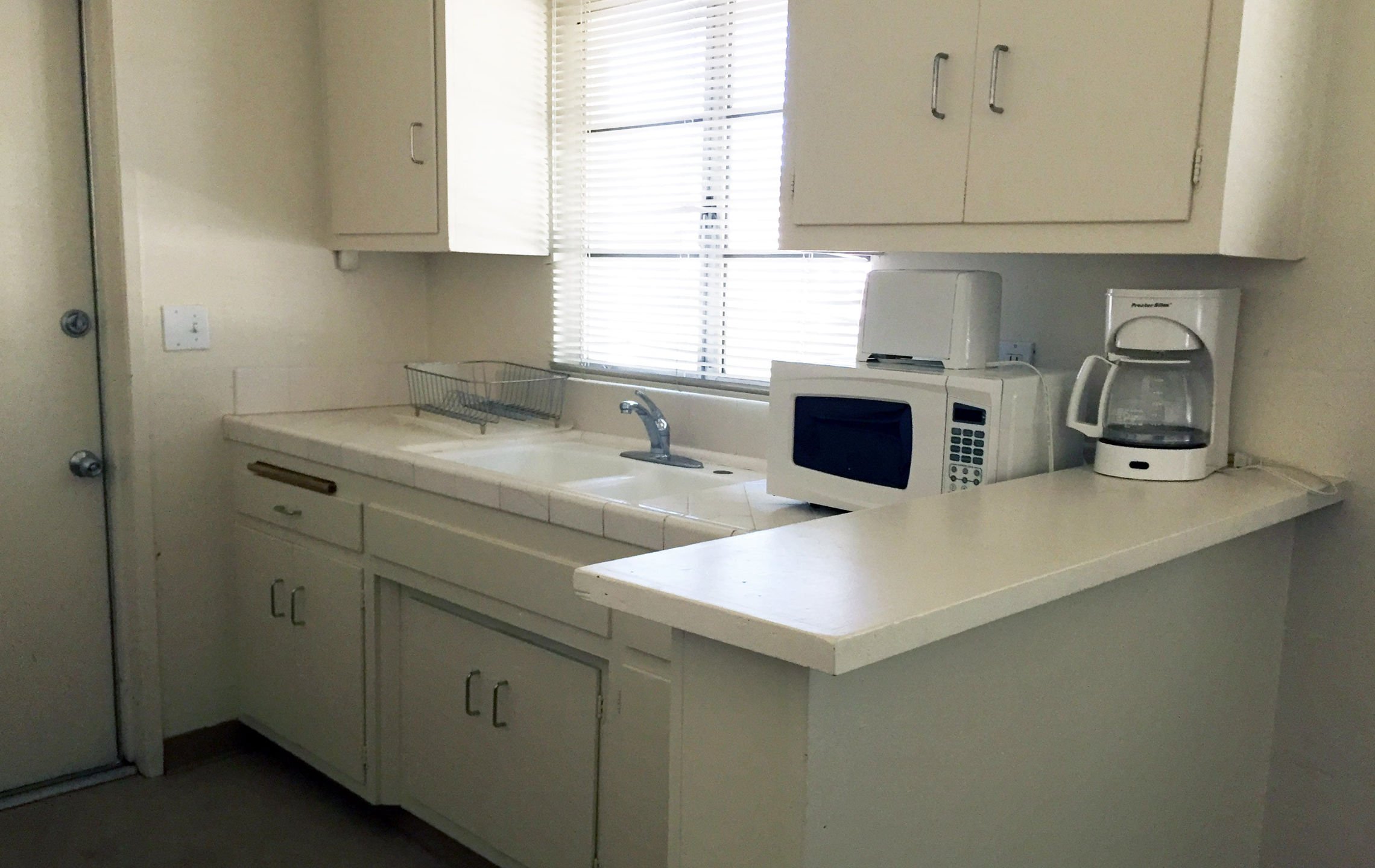 a kitchen with white cabinets and a microwave