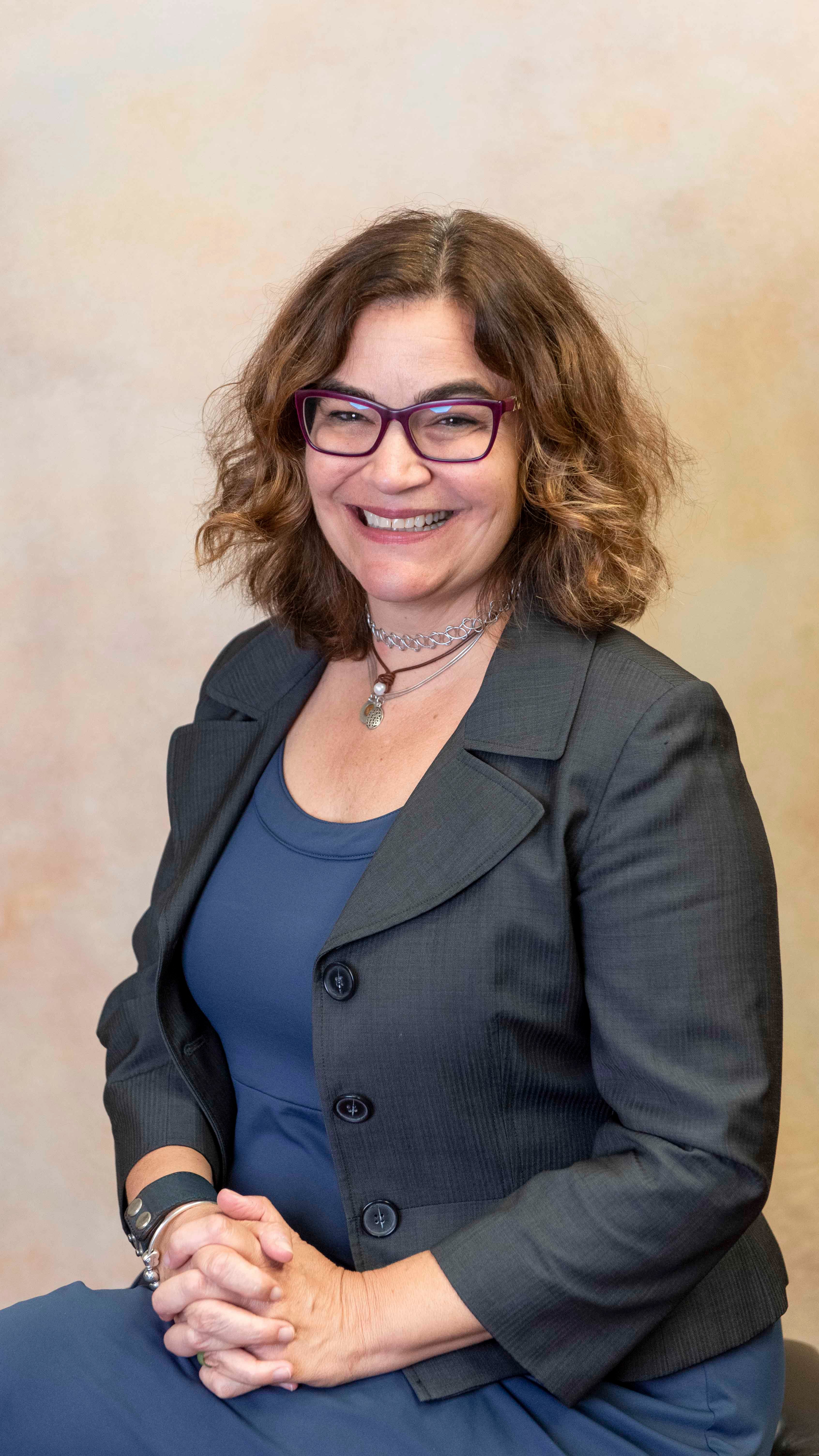 a woman wearing glasses and a grey jacket