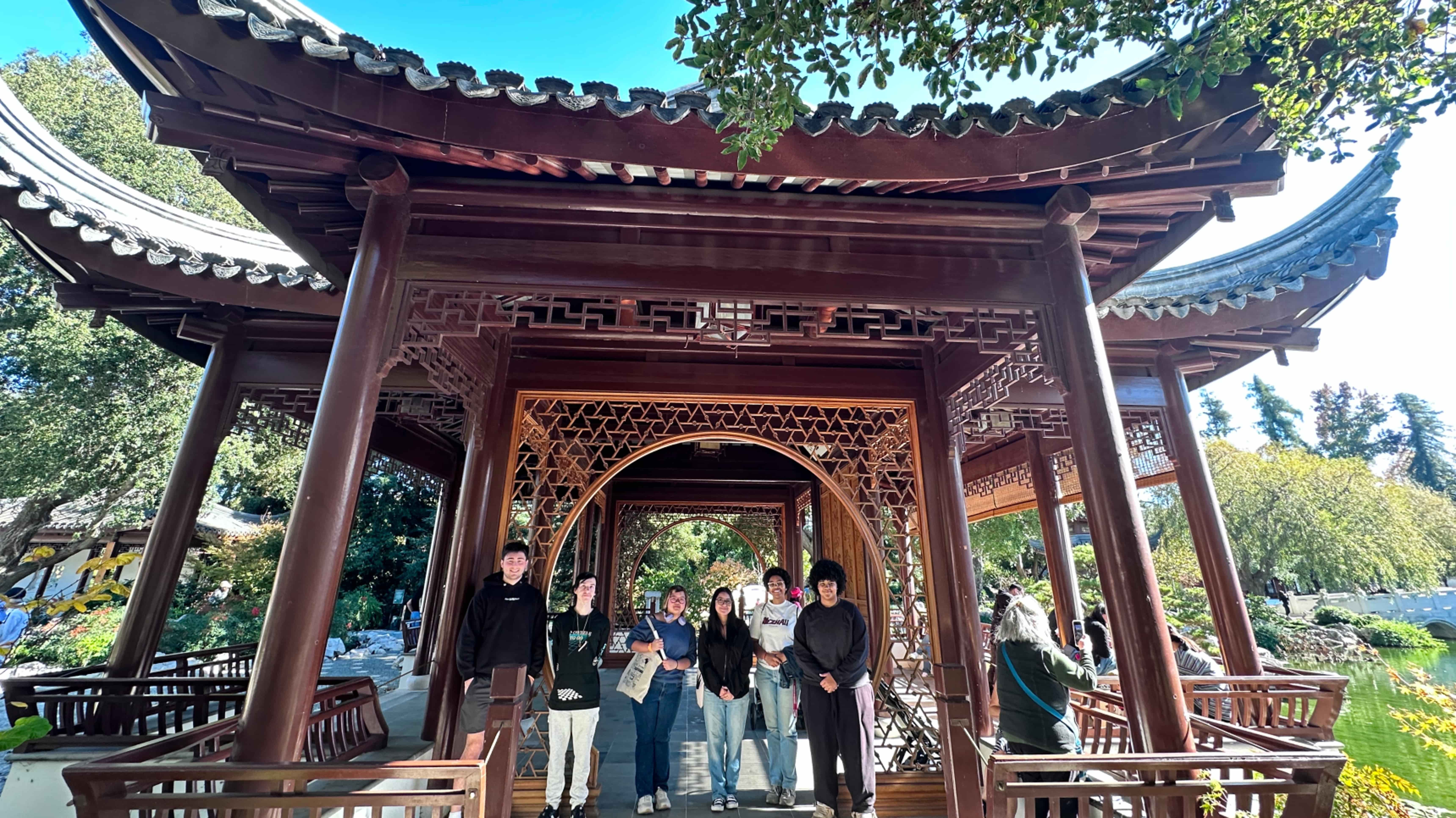 a group of people standing under a wooden structure