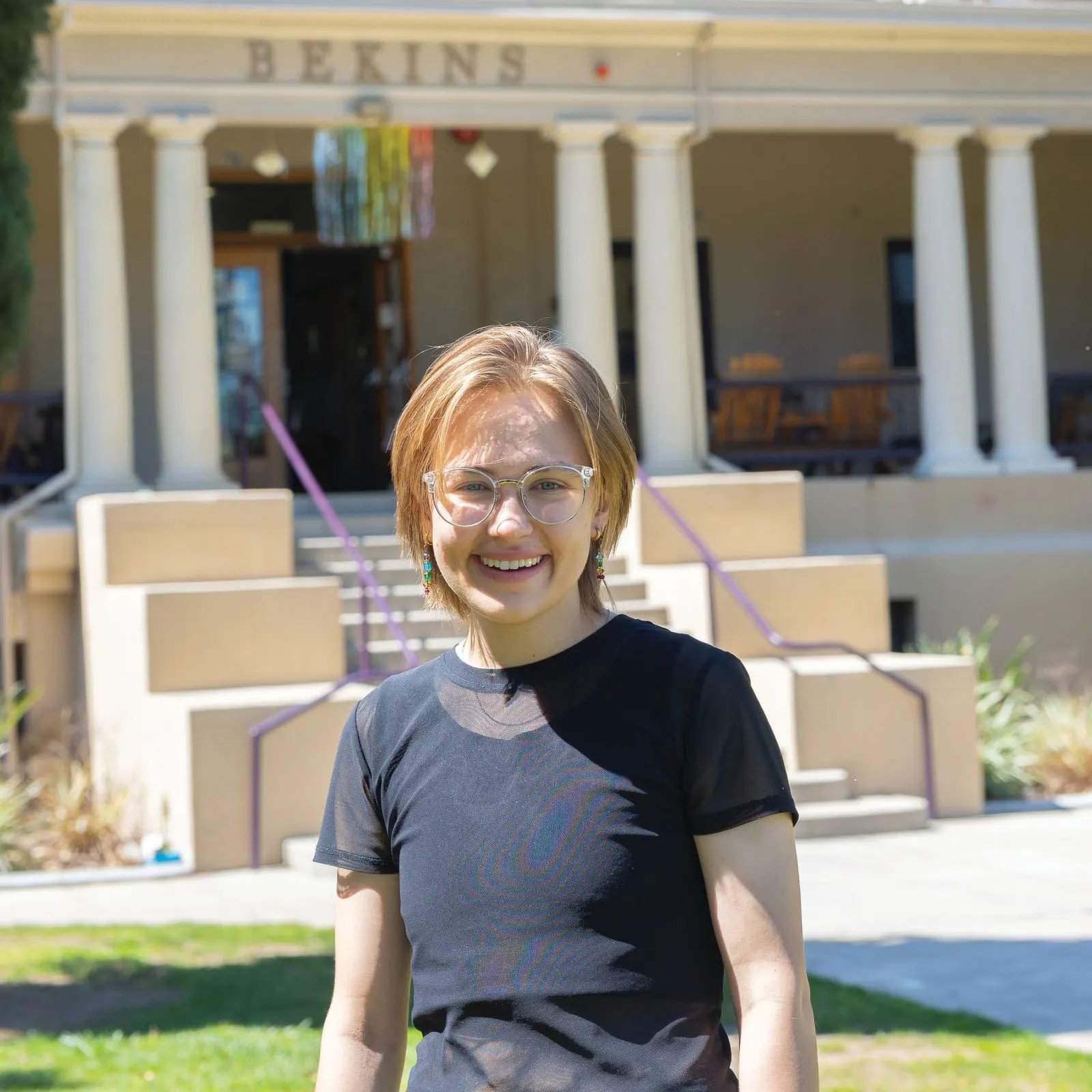 a woman smiling in front of a building