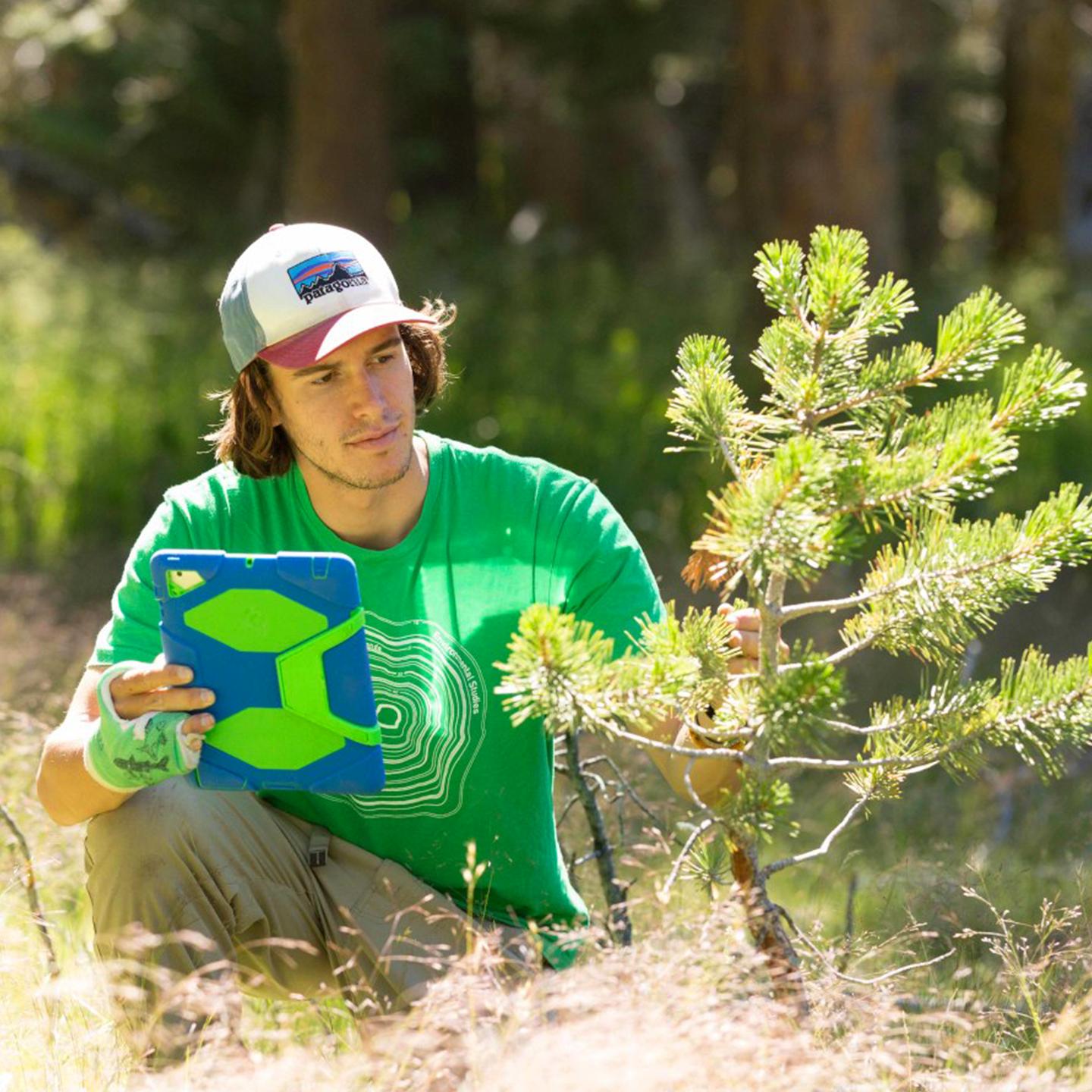 a man sitting in the woods holding a tablet