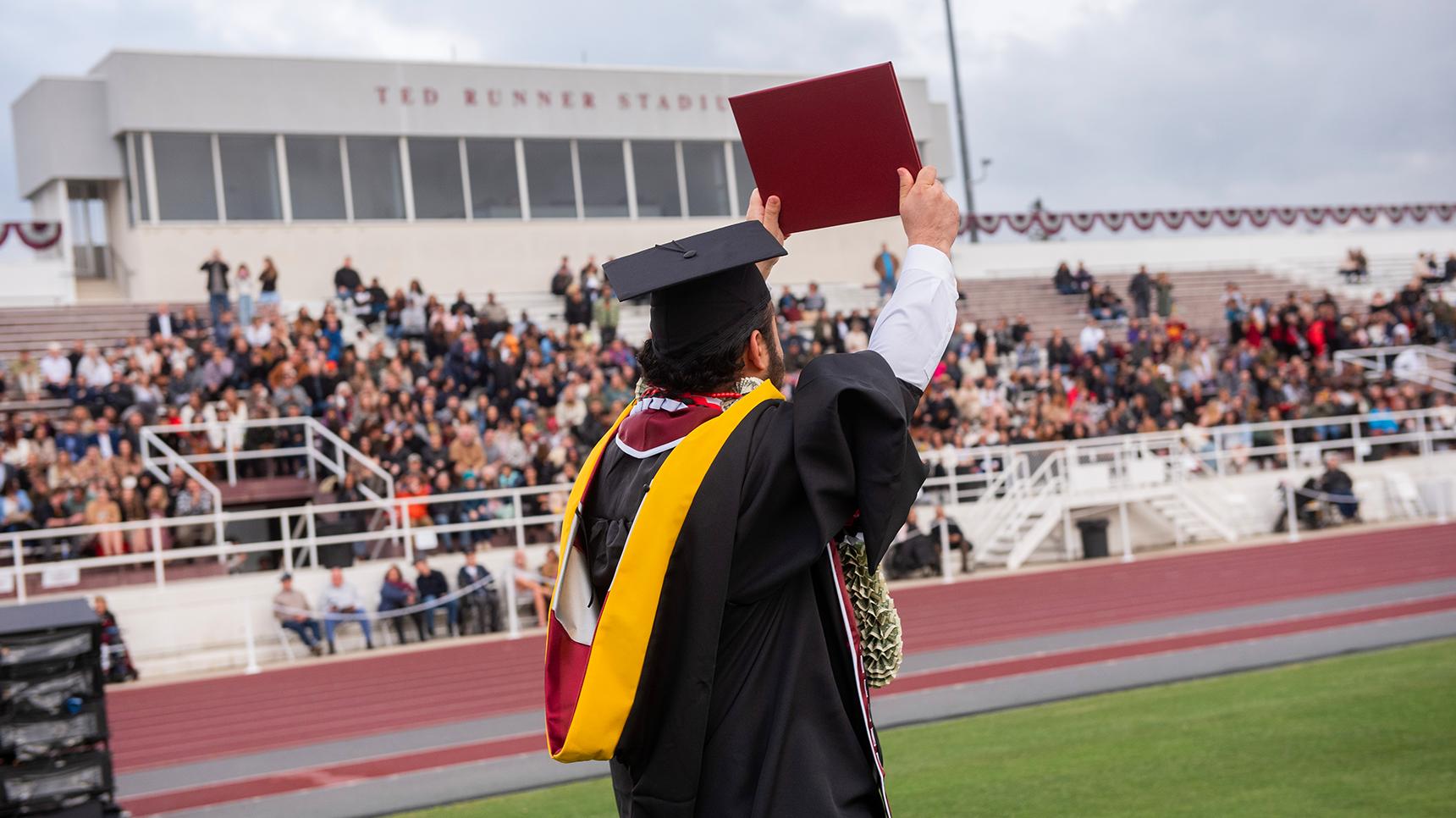 a man in a graduation gown holding a diploma