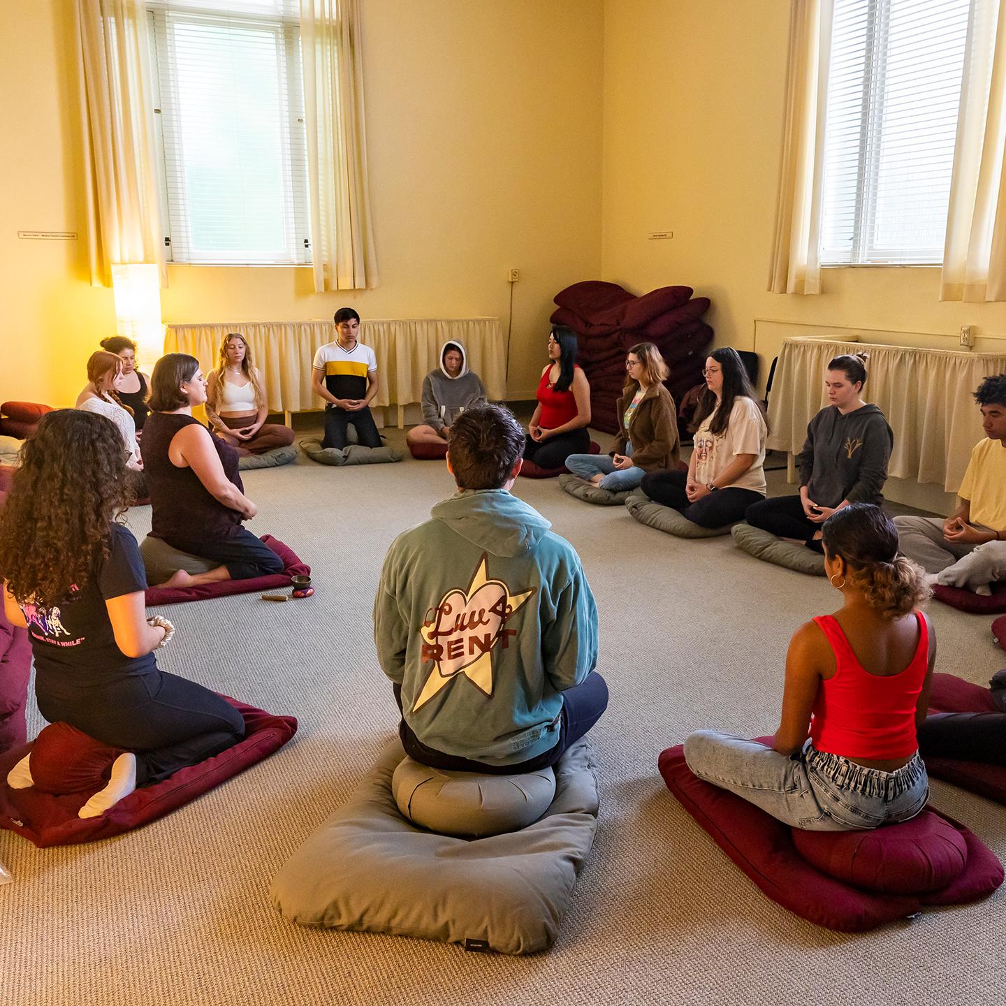 a group of people sitting on floor in a circle