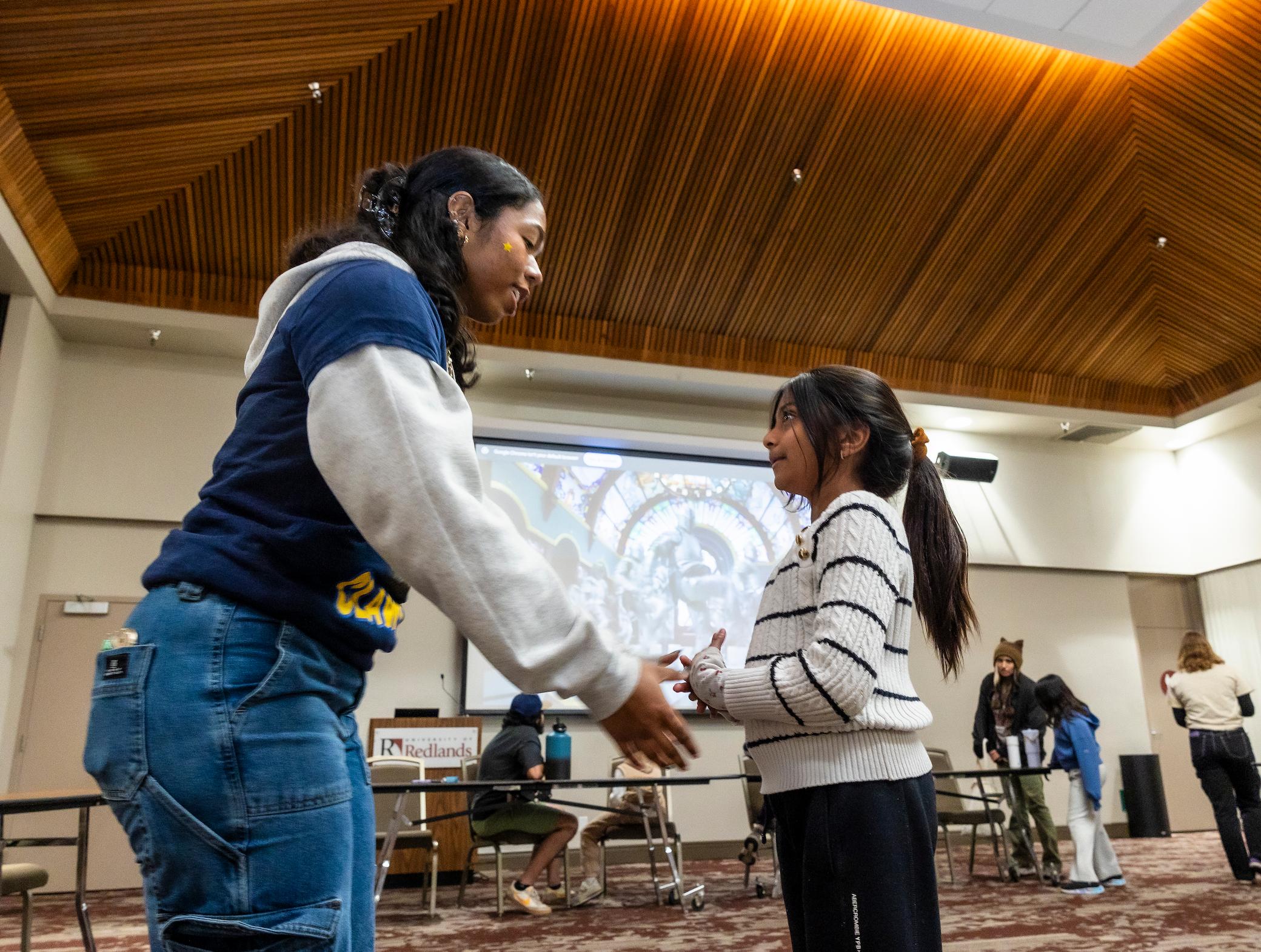 a two girls holding hands in a room
