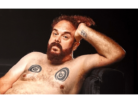 a man with a beard and mustache with tattoos on his chest