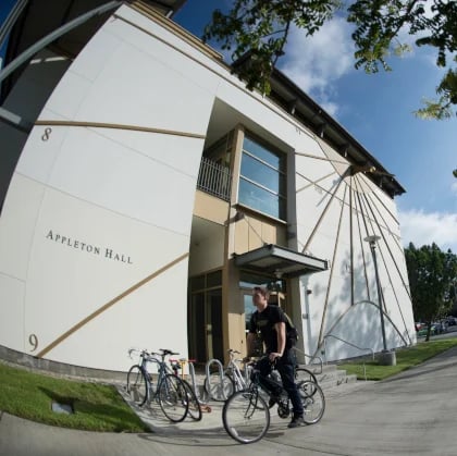 a man standing on a bicycle outside of a building