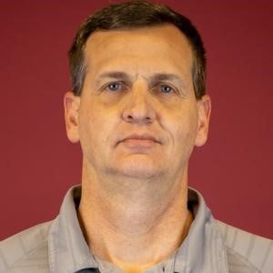 a man with short brown hair wearing a grey shirt