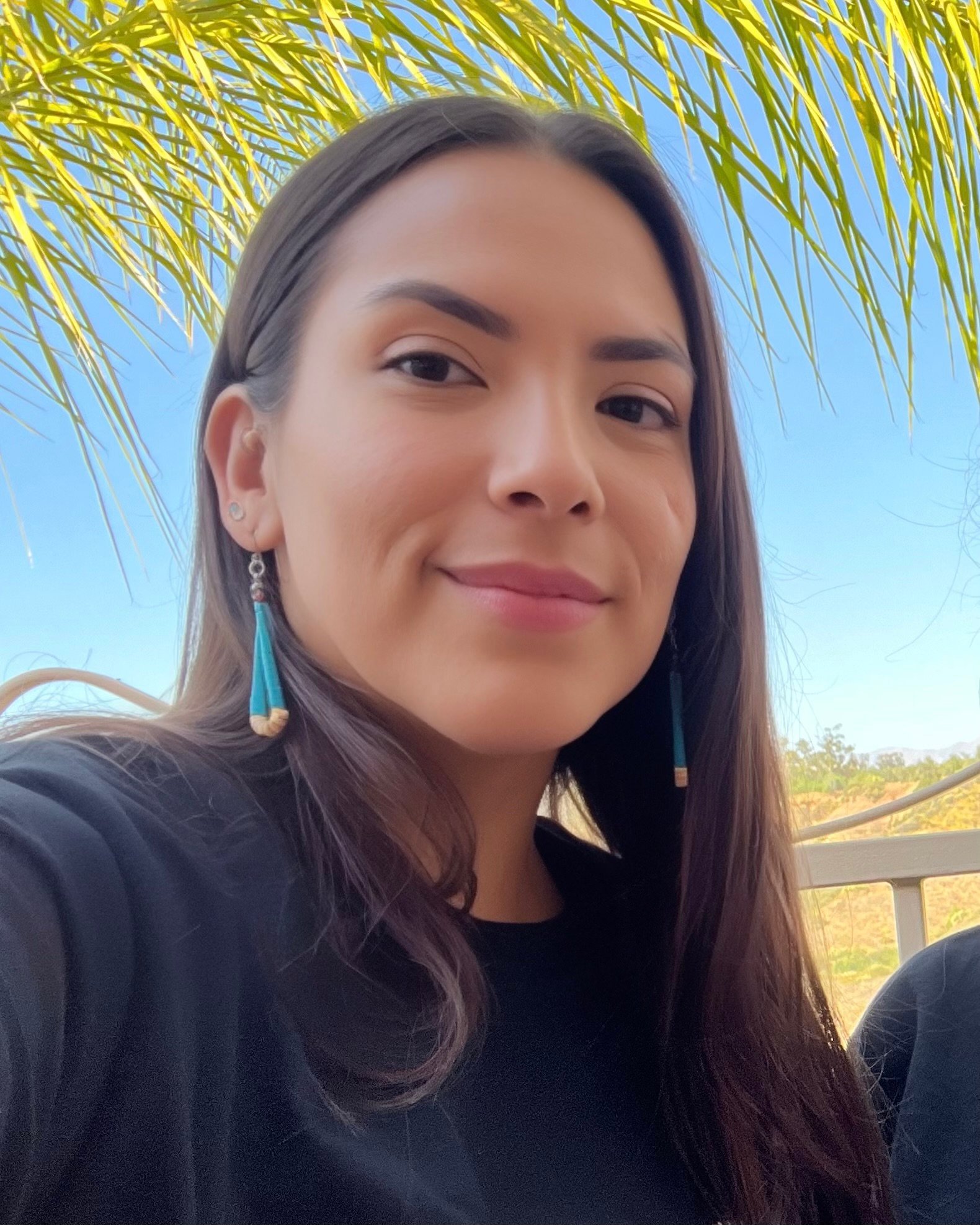a woman taking a selfie under a palm tree
