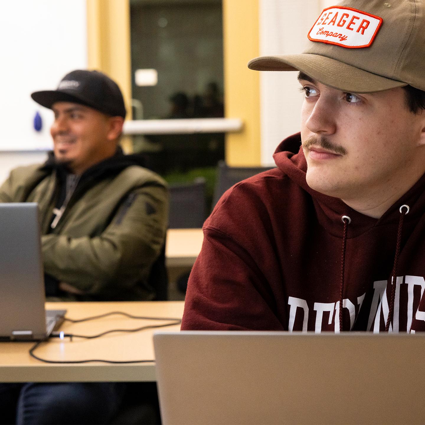 a man in a hat looking away from another man