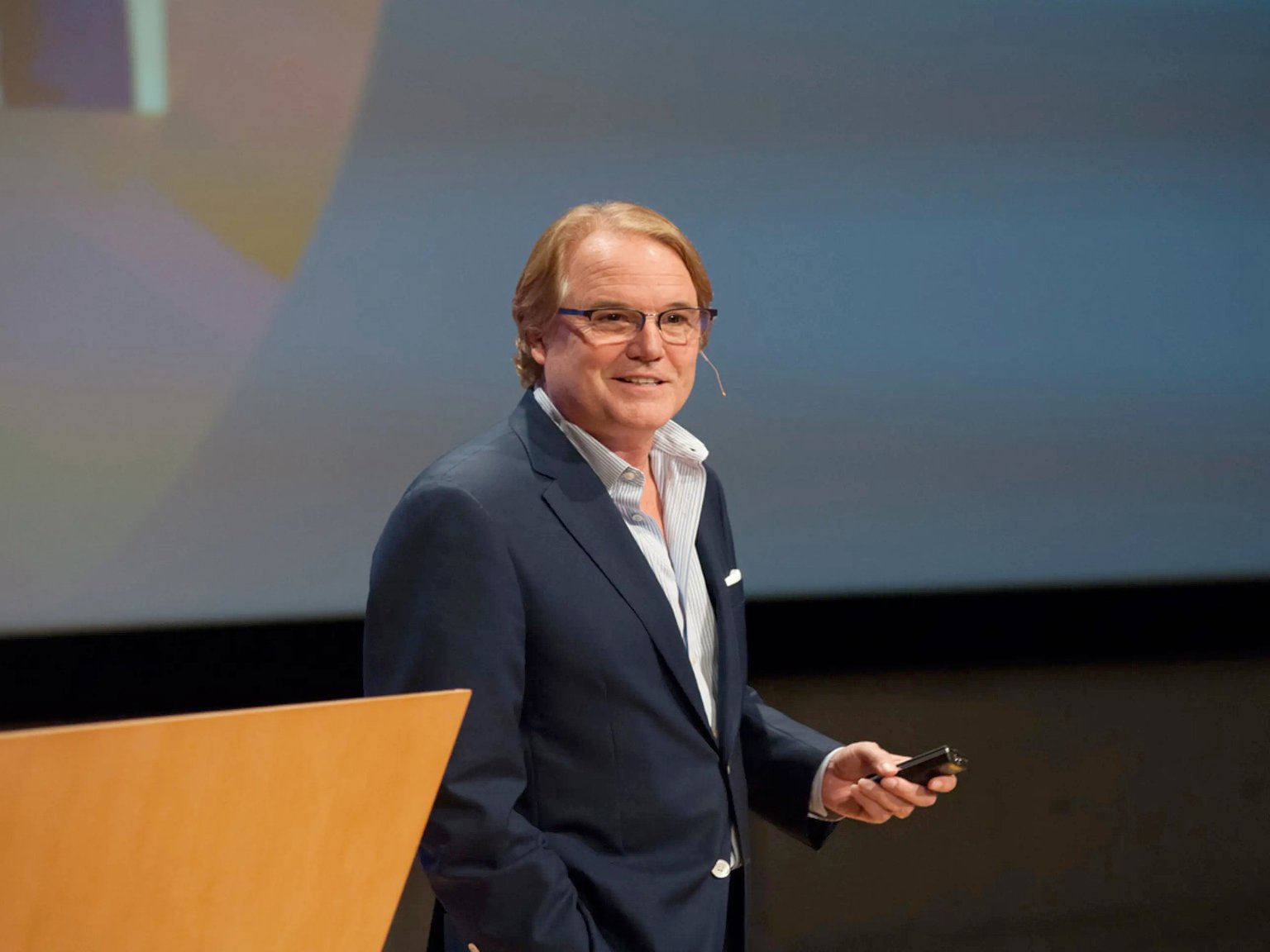 a man standing at a podium holding a phone