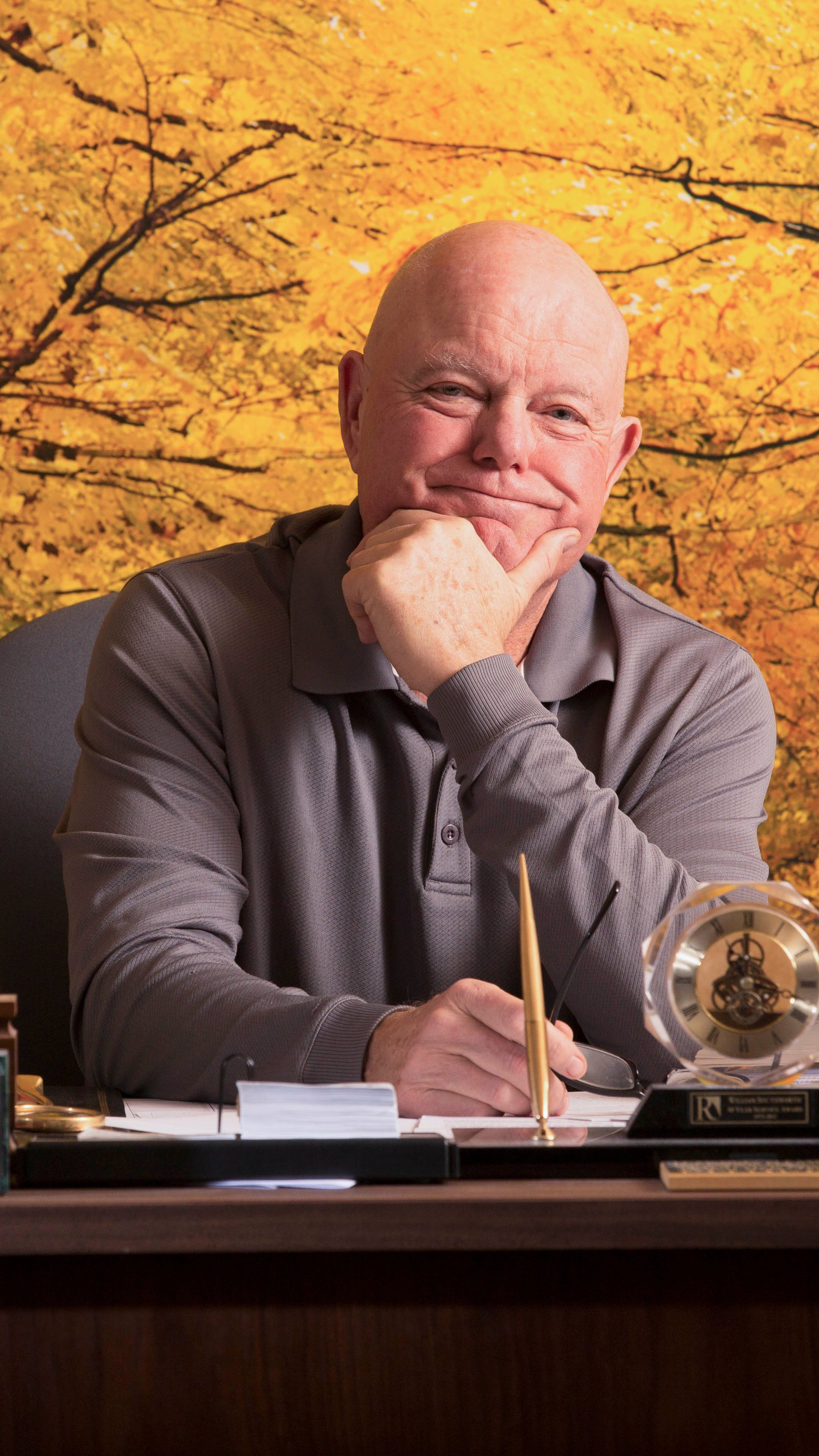 a man sitting at a desk with a pen and a trophy