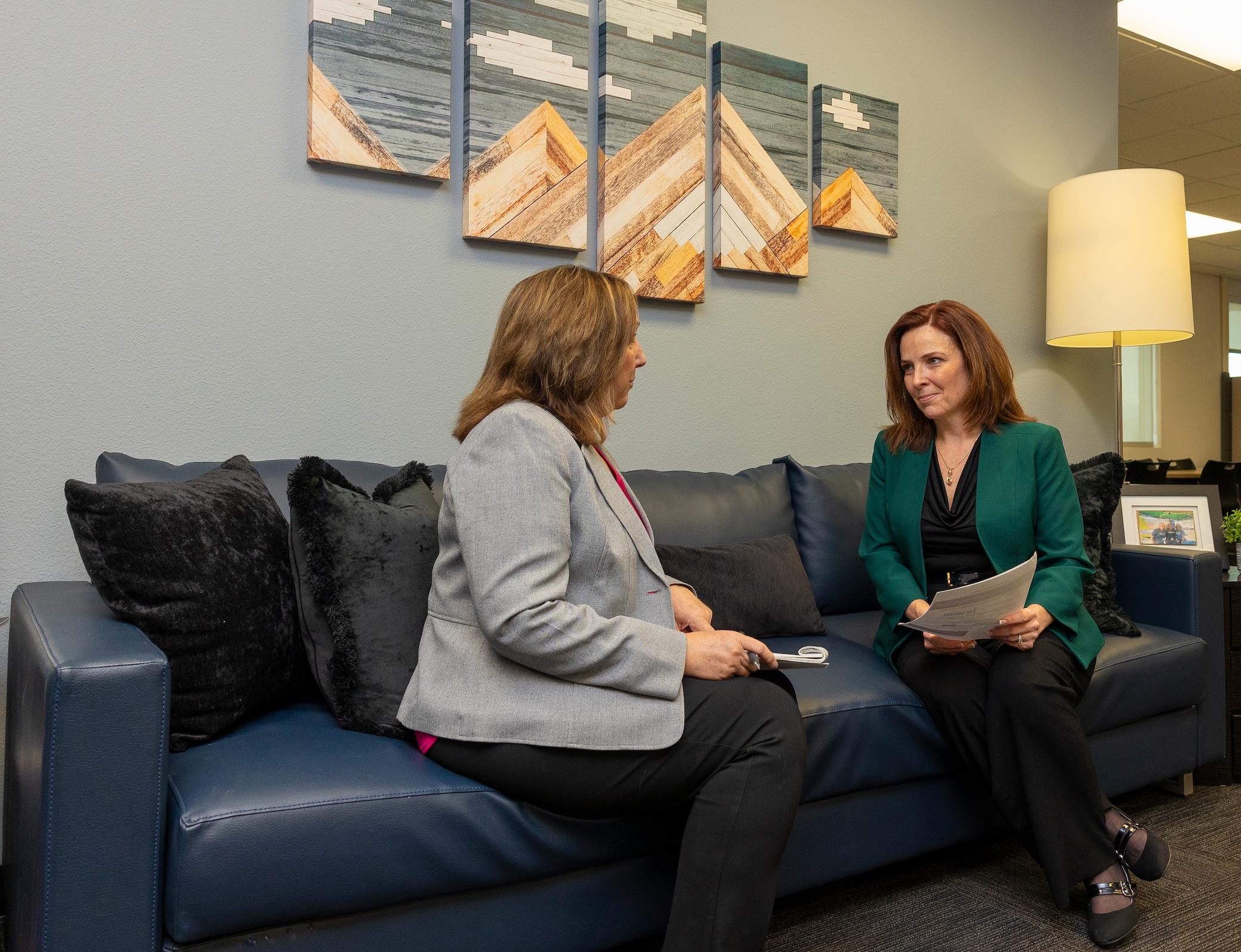 a woman sitting on a couch talking to another woman