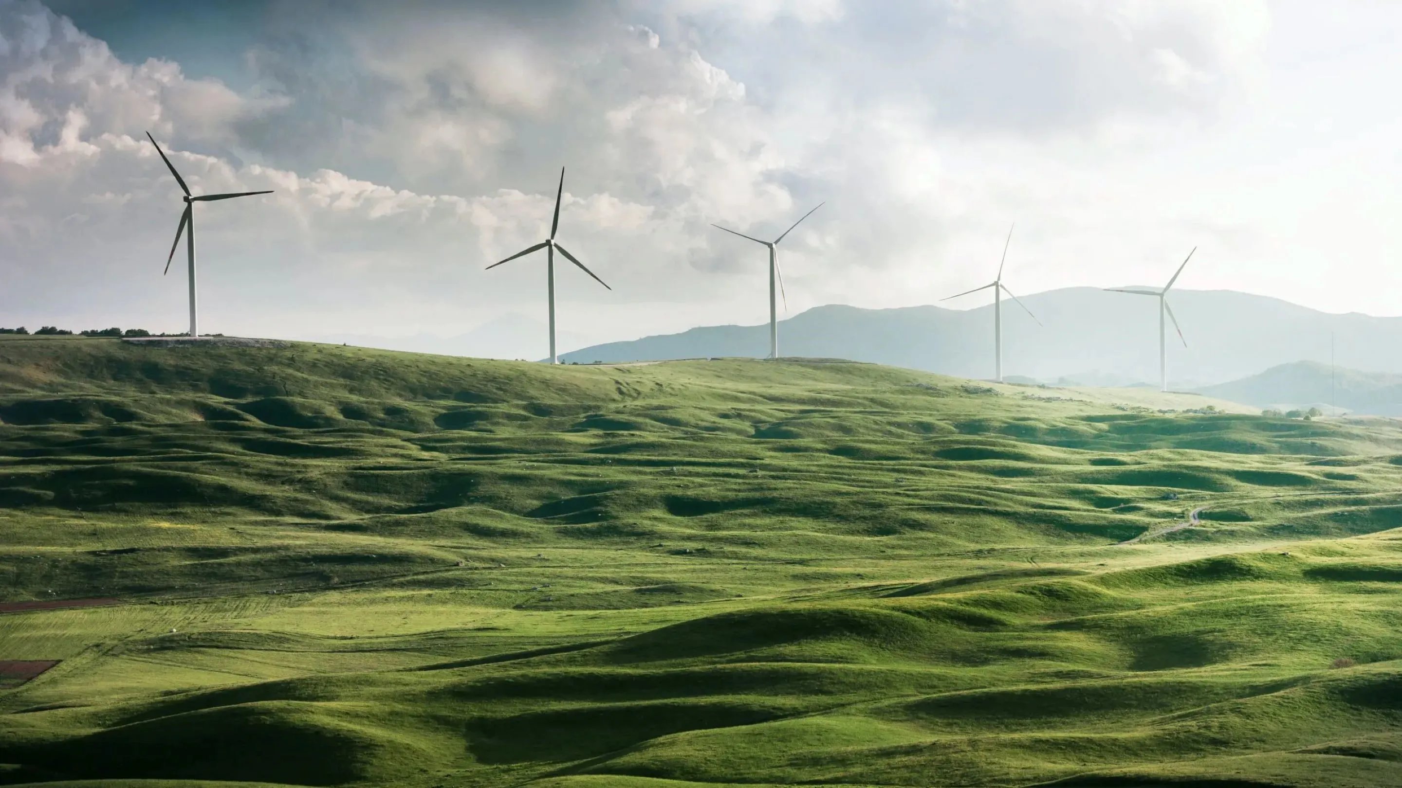 a group of wind turbines on a green hill