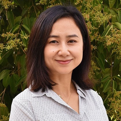 a woman smiling in front of a bush