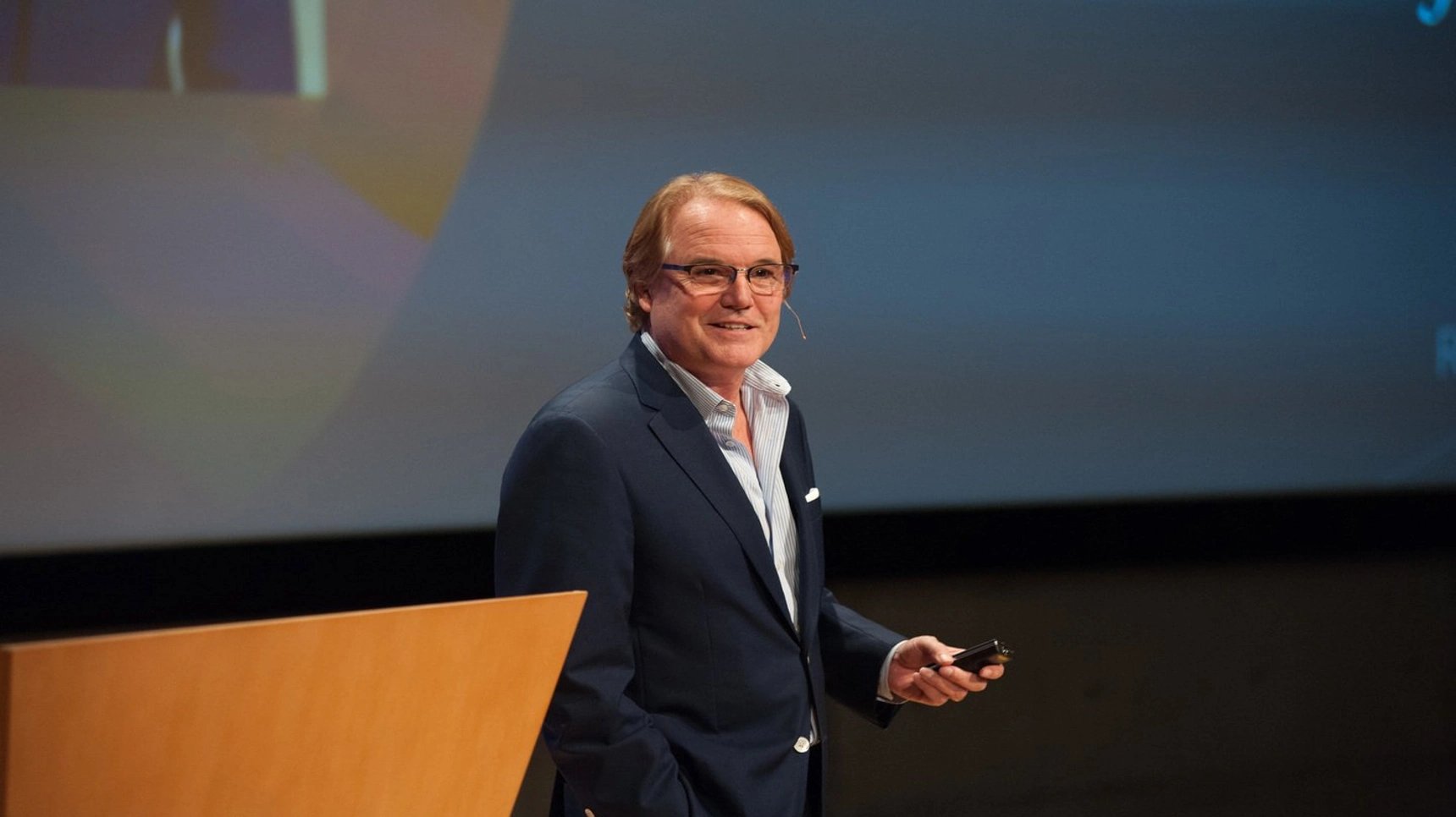 a man standing at a podium holding a phone