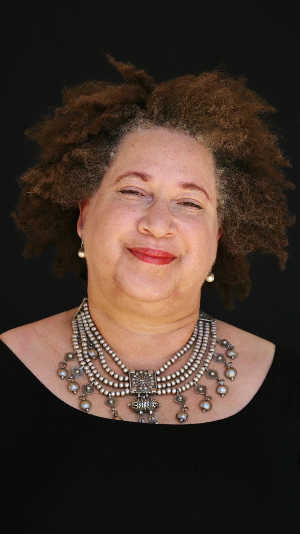 a woman with curly hair wearing a necklace