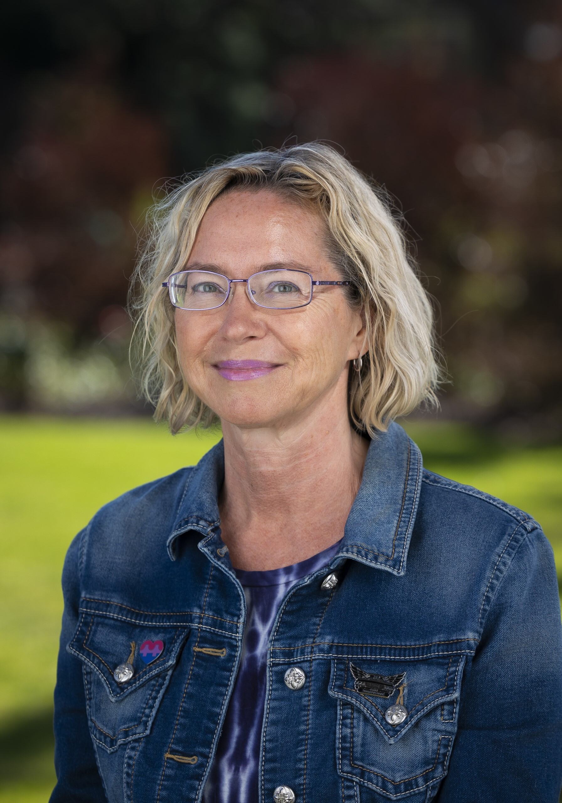 a woman wearing glasses and a denim jacket