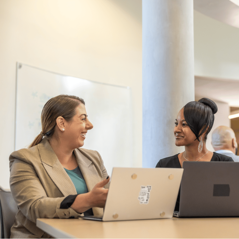 a group of women sitting at a table with laptops