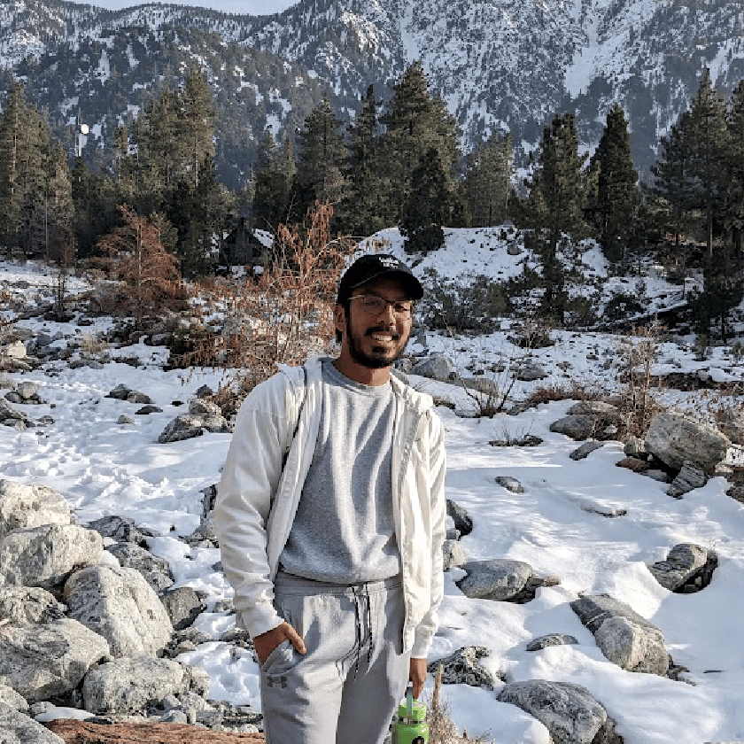 a man standing in snow with trees and mountains in the background