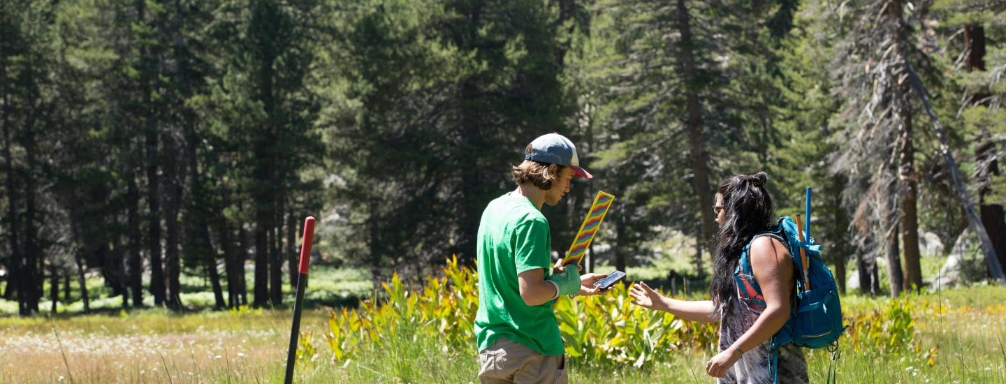 a man holding a candy and a woman standing in a field