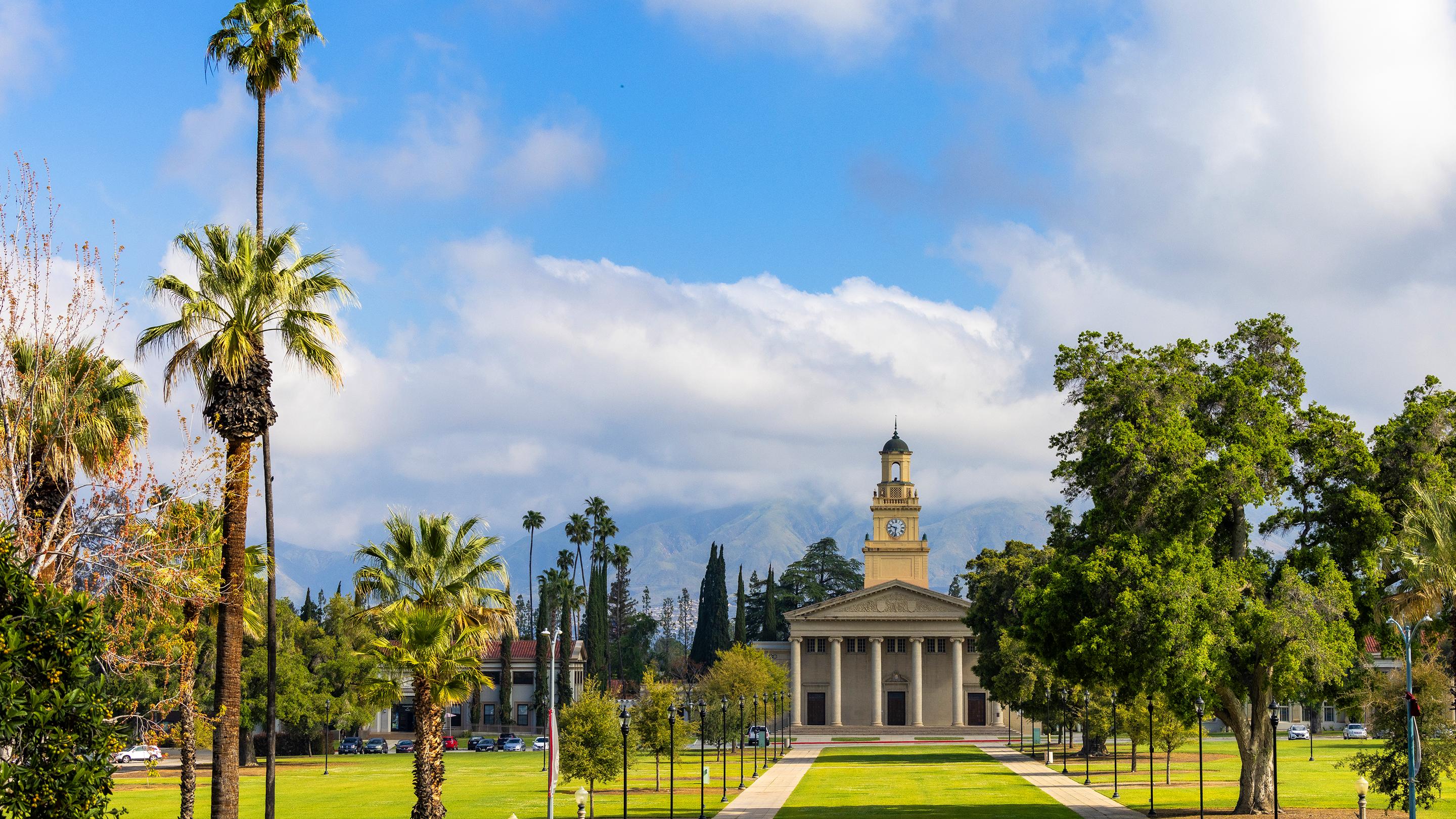 a building with a clock tower and grass and trees