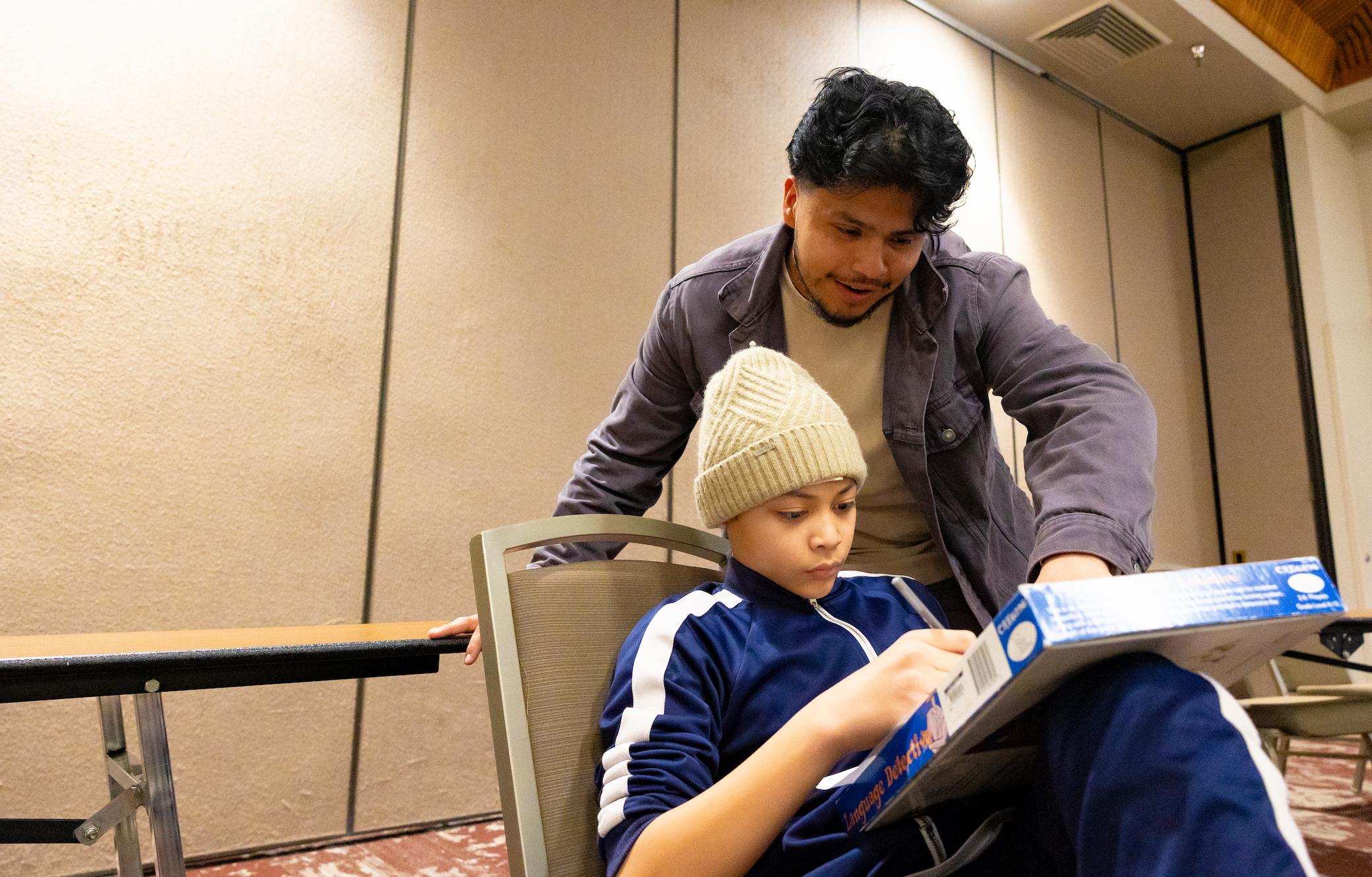 a man and boy sitting in a chair looking at a book