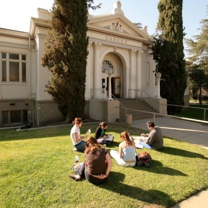 a group of people sitting on the grass outside of a building