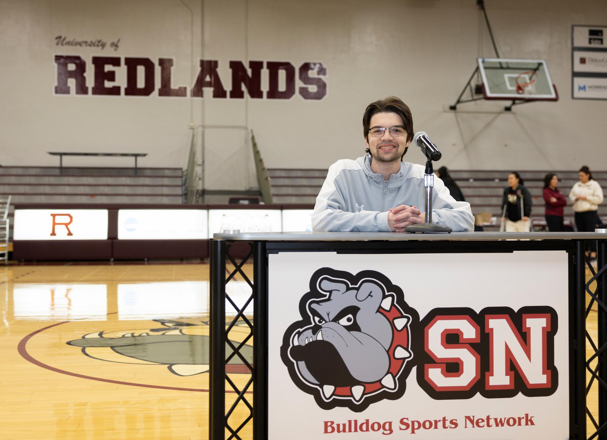 a man standing behind a microphone in a gym