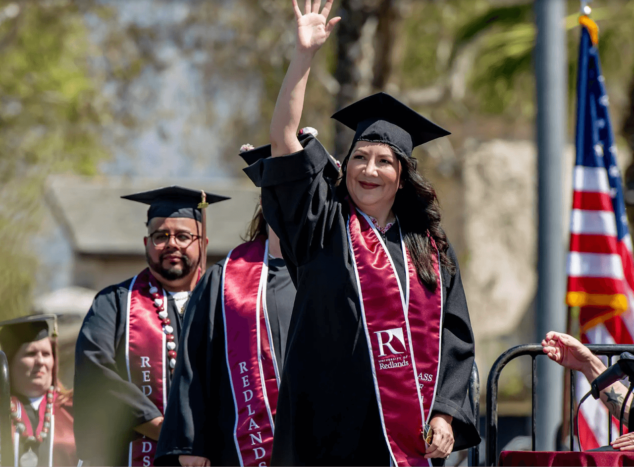 a woman in graduation gown and cap waving