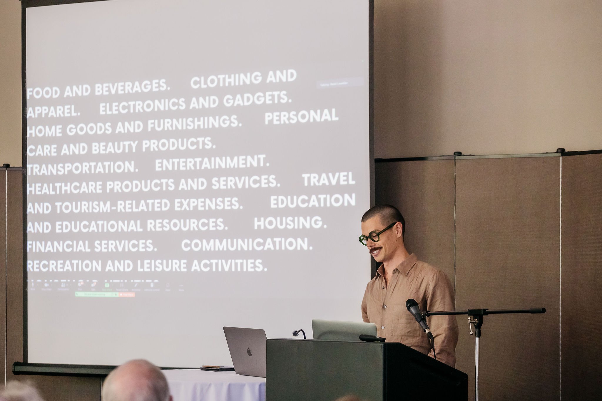 a man standing at a podium with a screen behind him