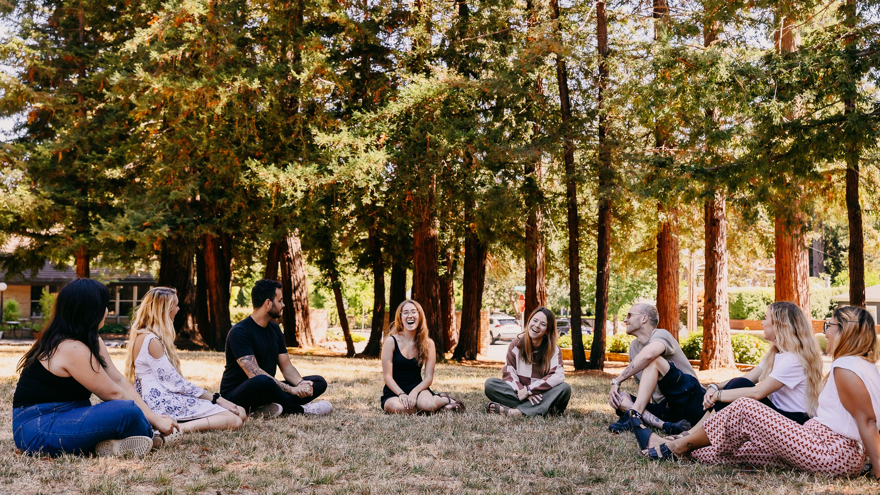 a group of people sitting on grass in a park