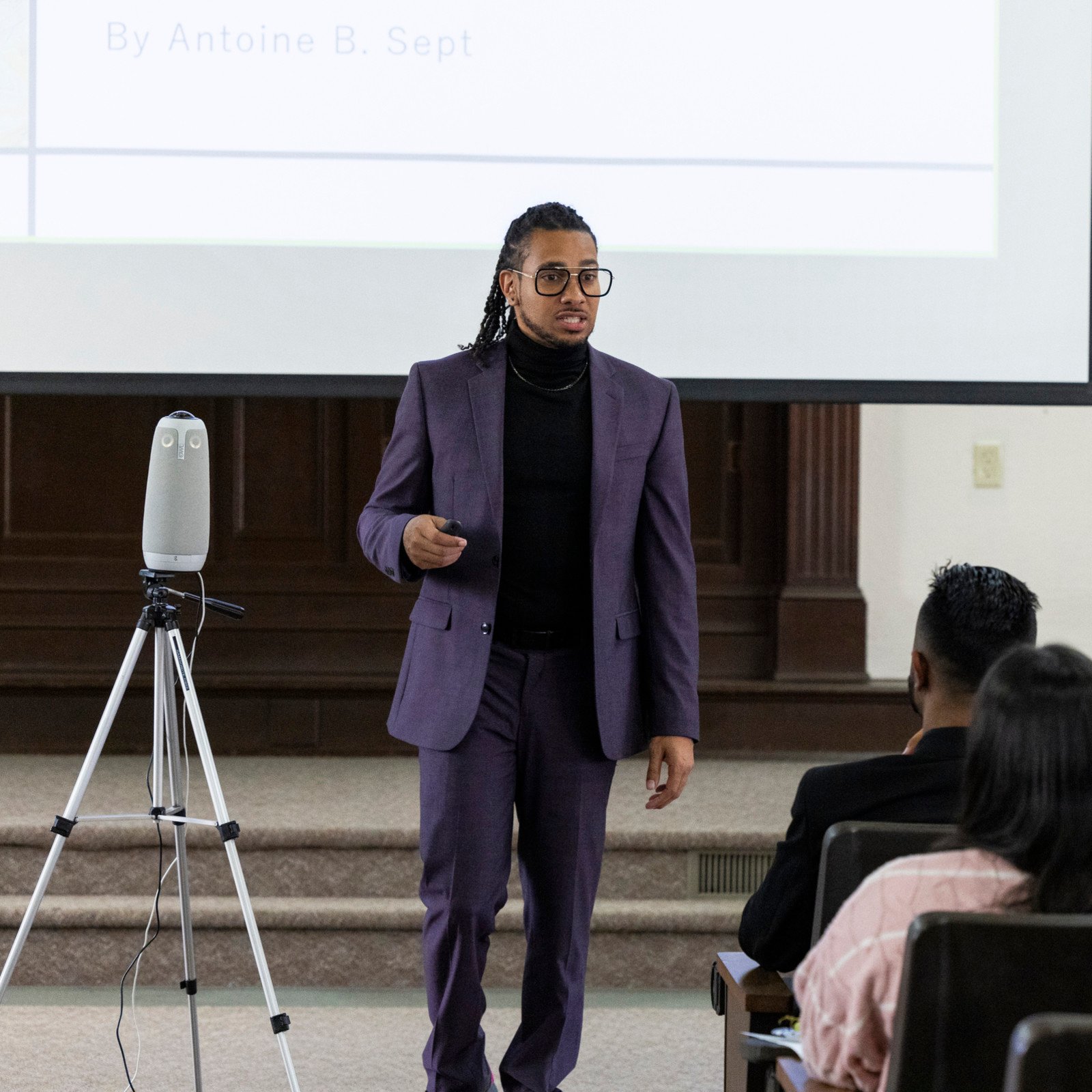 a man in a suit standing in front of a projector screen
