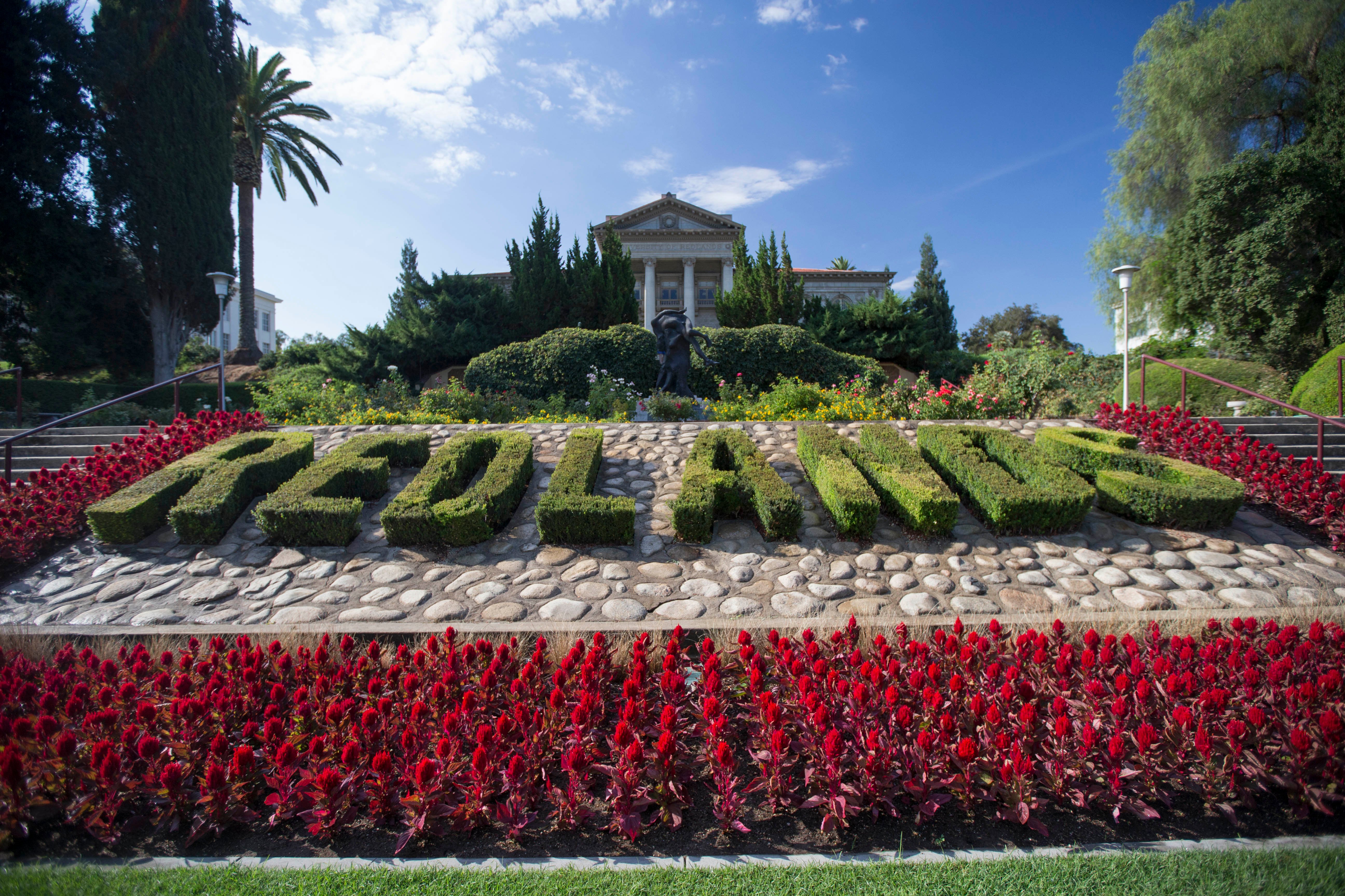 a sign with plants and flowers in front of a building