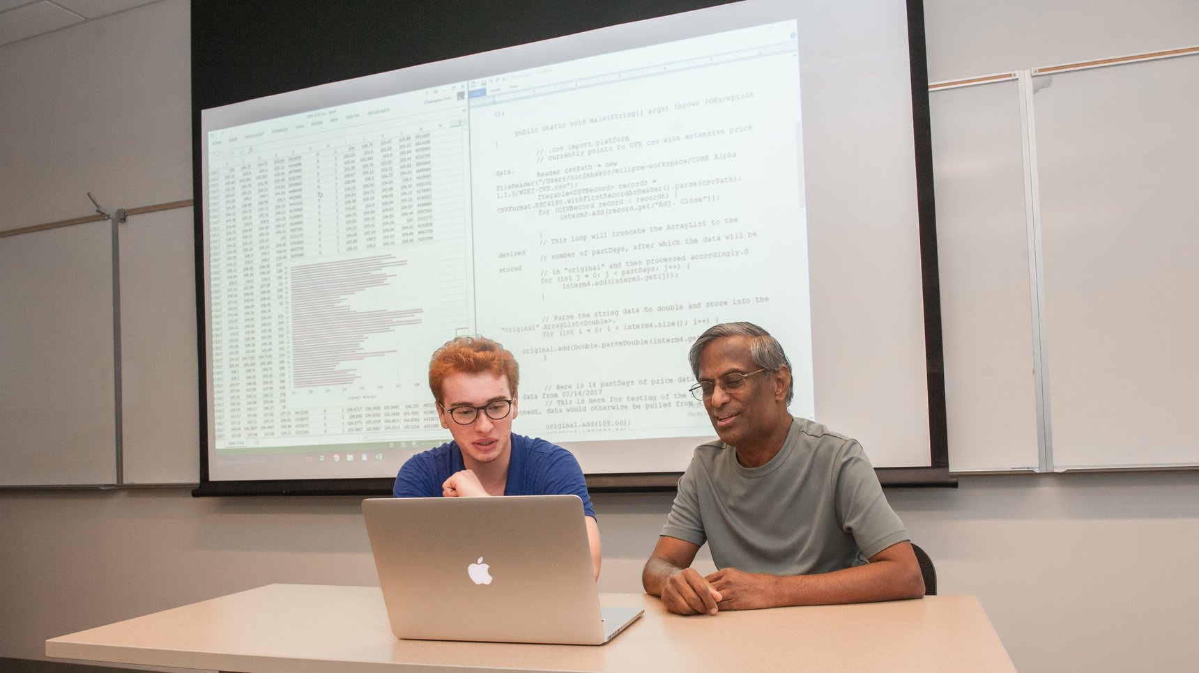 a man and woman sitting at a table looking at a laptop