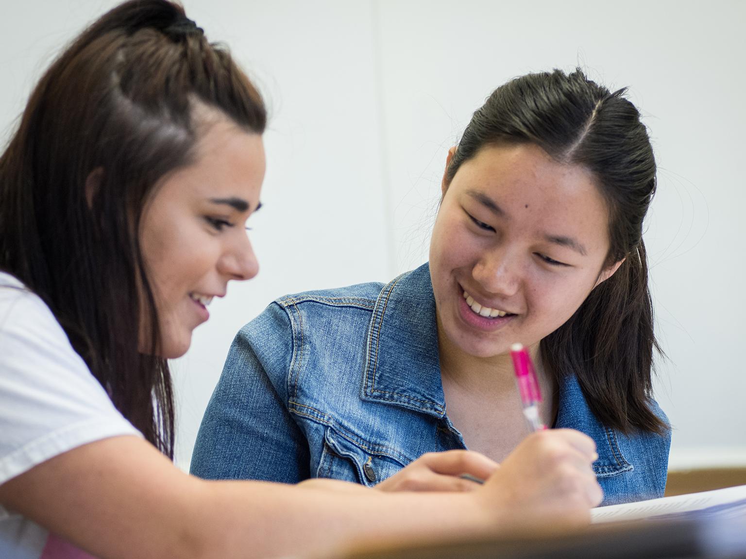 a couple of girls looking at a pen