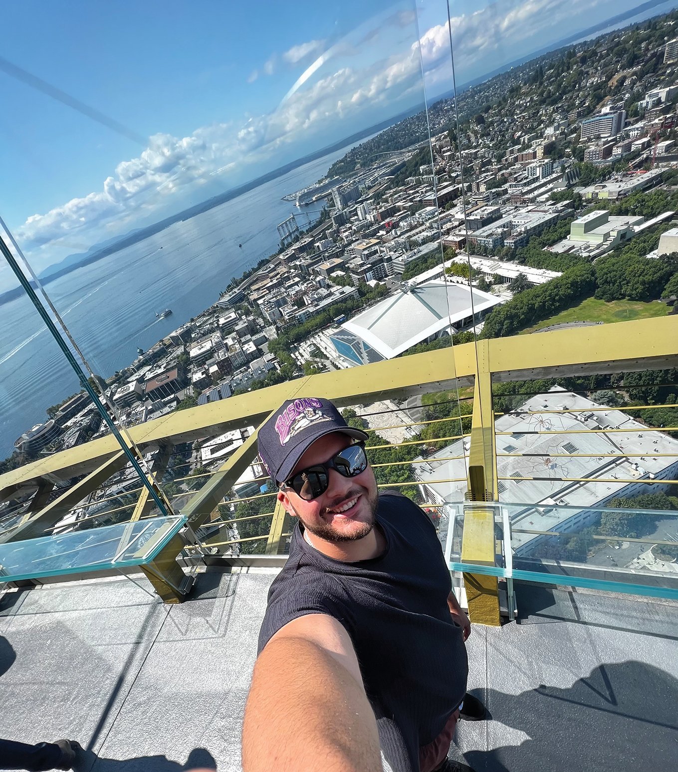 a man taking a selfie on a glass platform above a city