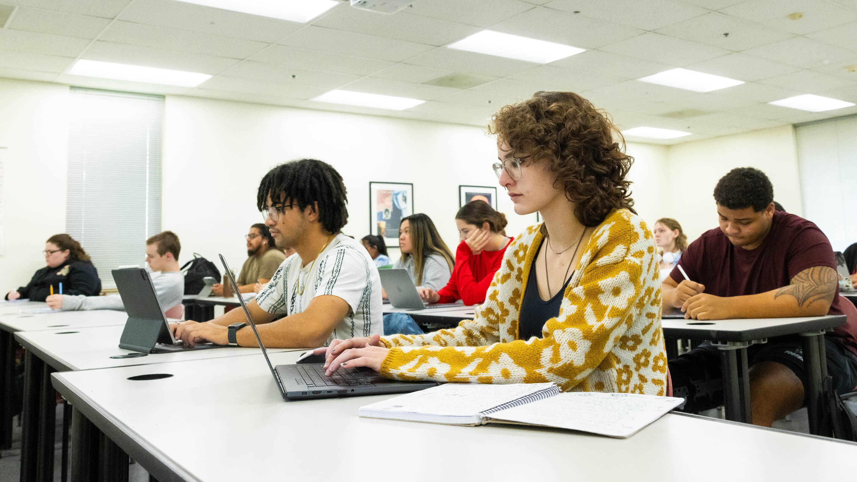 a group of people sitting at a table with laptops