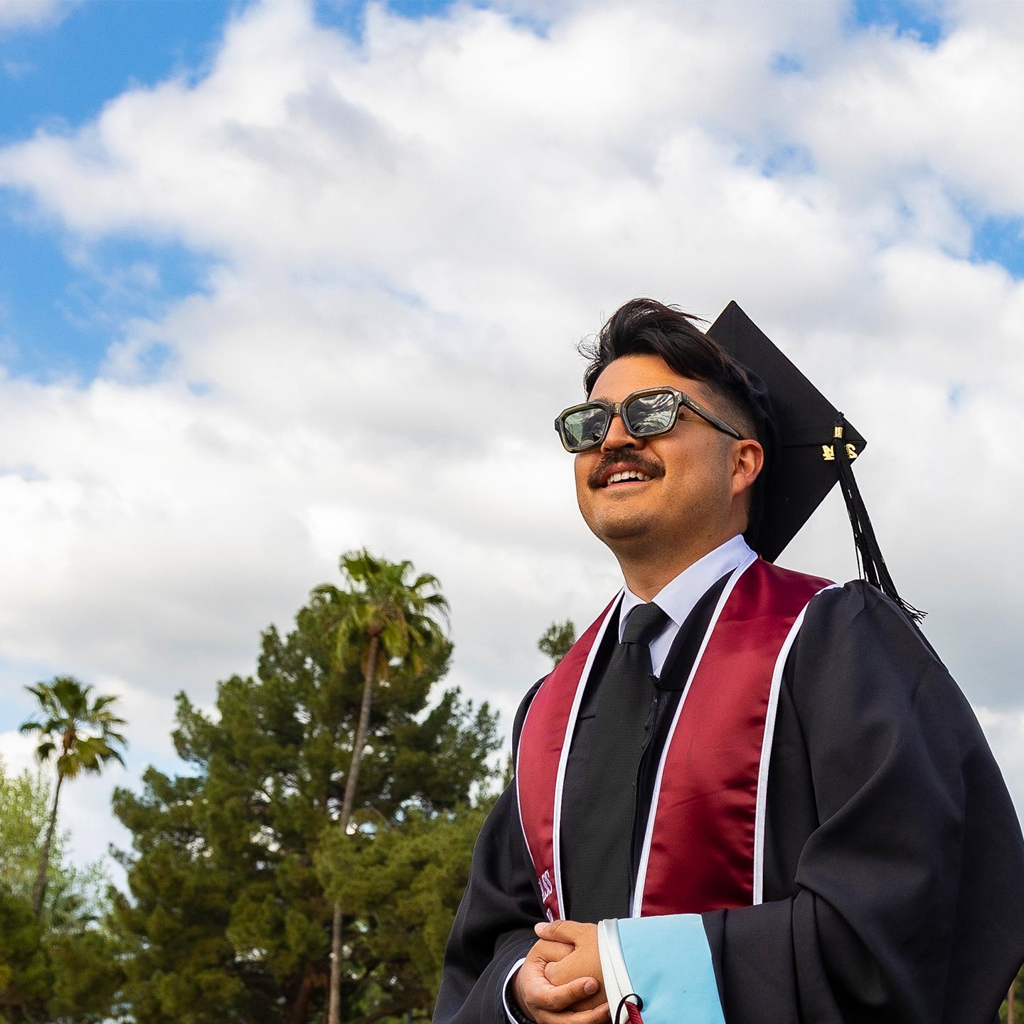 A graduate student wearing sunglasses is looking ahead.