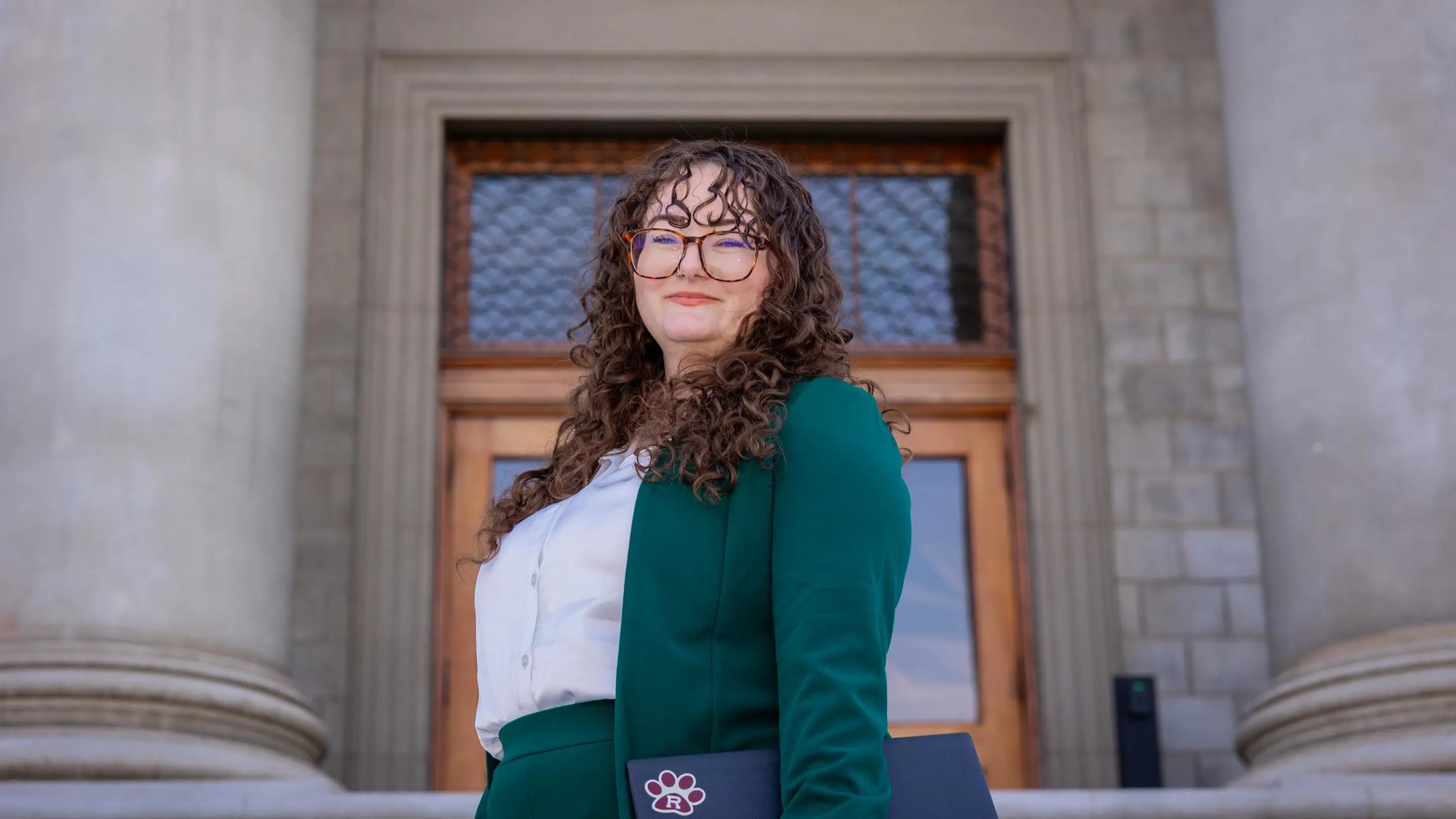a woman in green suit and glasses smiling