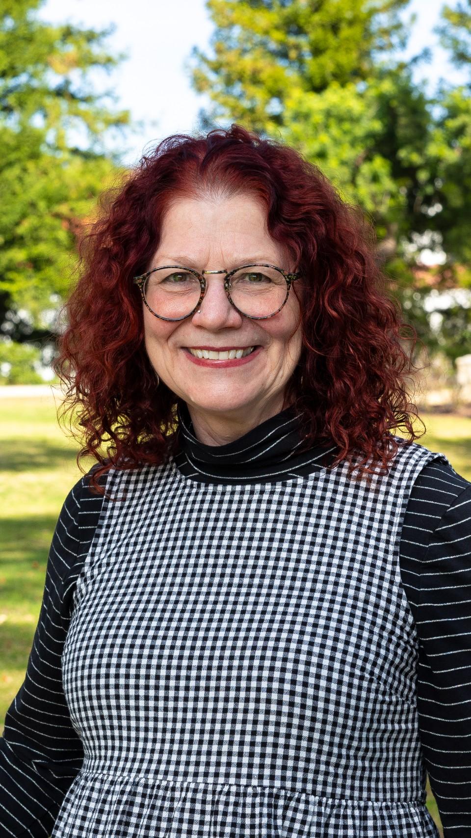 a woman with red curly hair wearing glasses