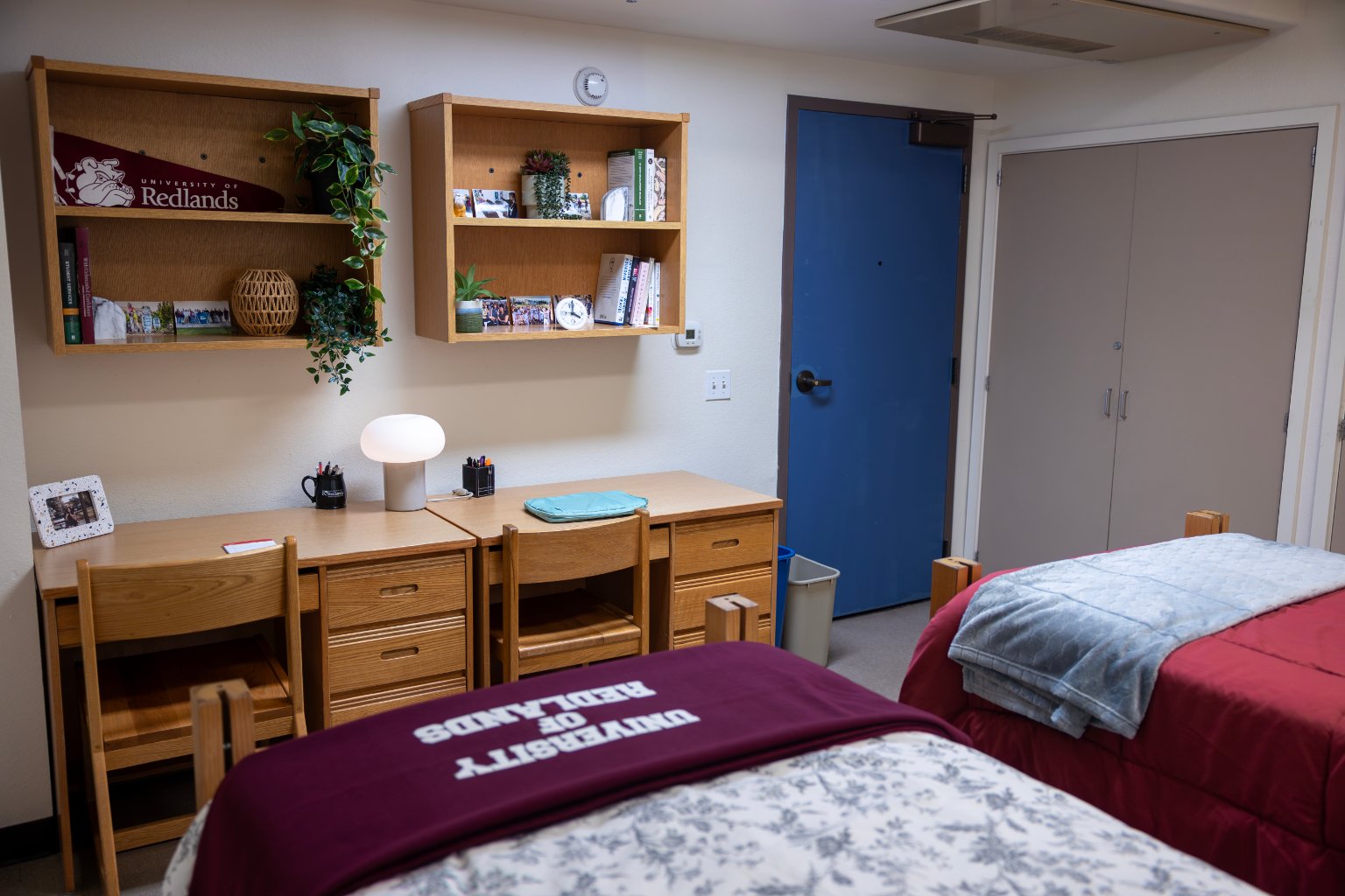 a room with two beds and desks and a blue door