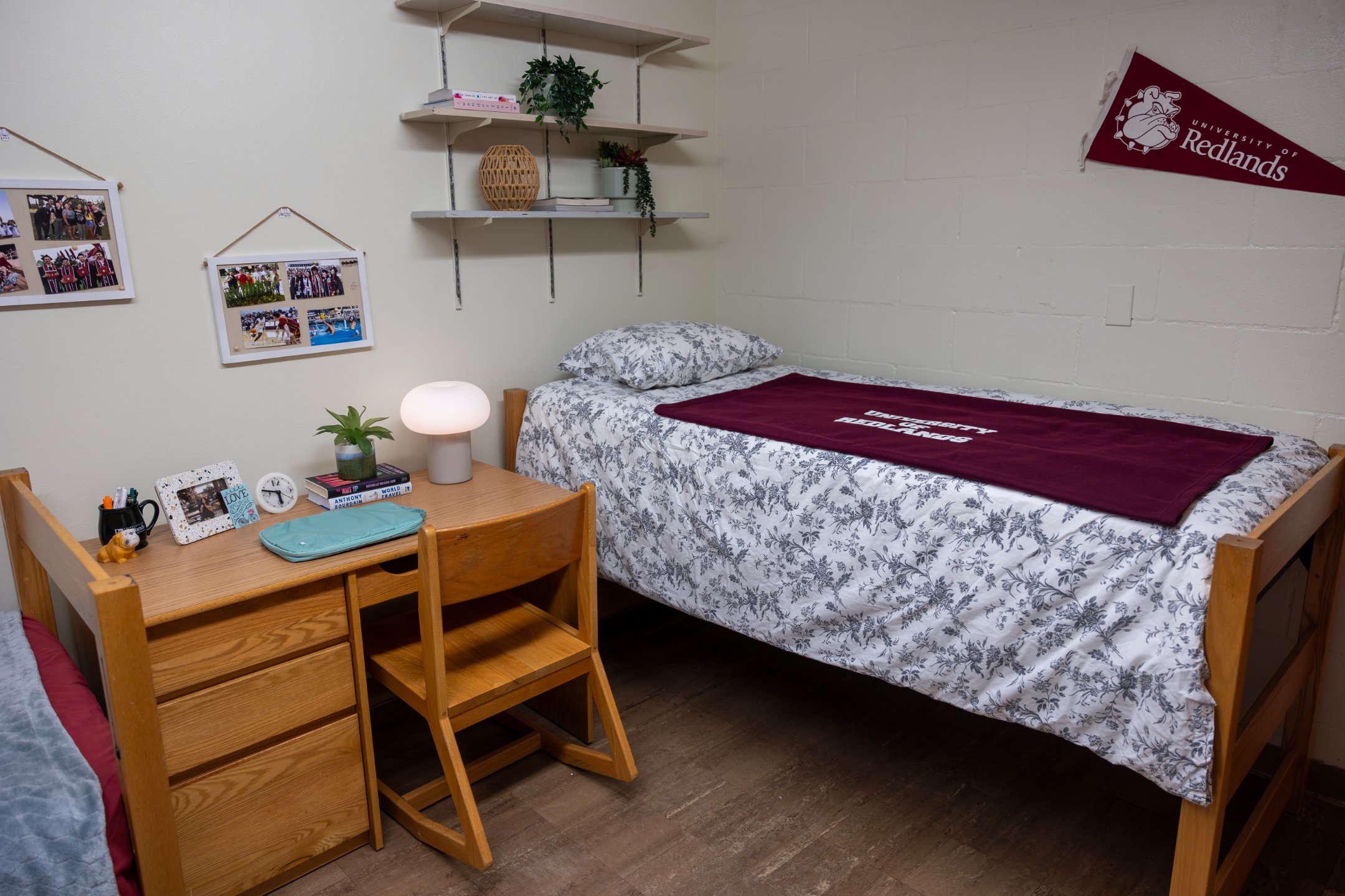 a bed with a red blanket and a desk in a room