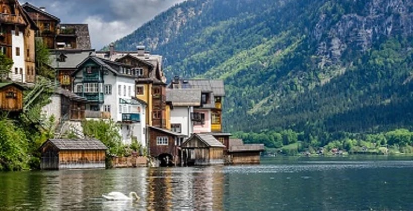 a lake with buildings and mountains in the background