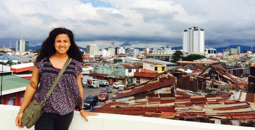 a woman standing on a ledge with a city in the background