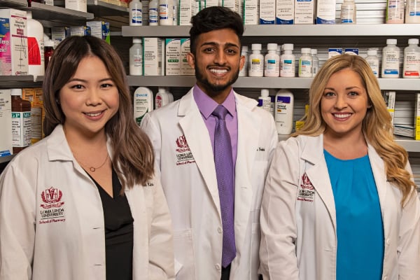 a group of people standing in front of a shelf of medicine